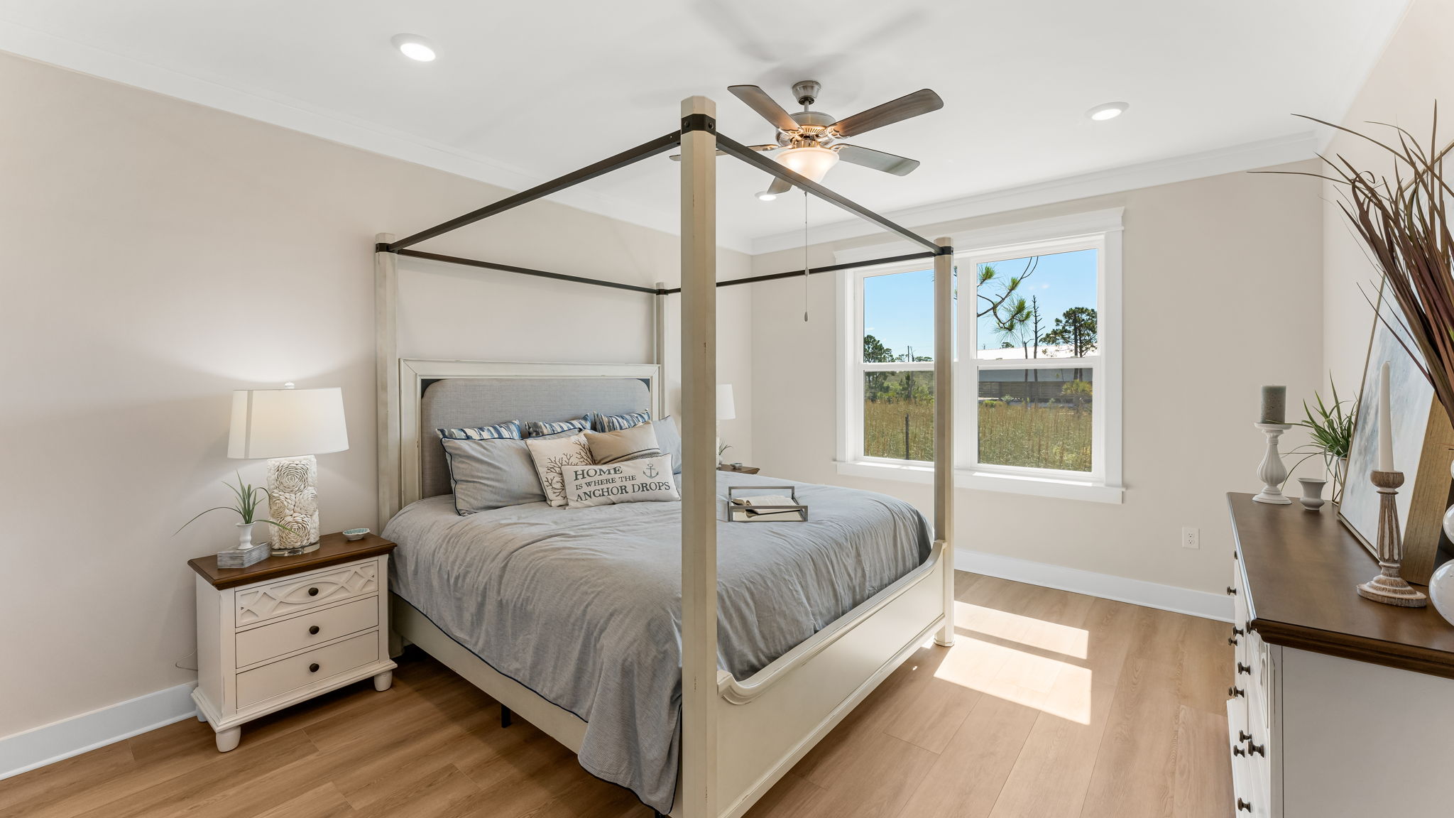 Furnished primary bedroom with EVP flooring and ceiling fan and two windows.