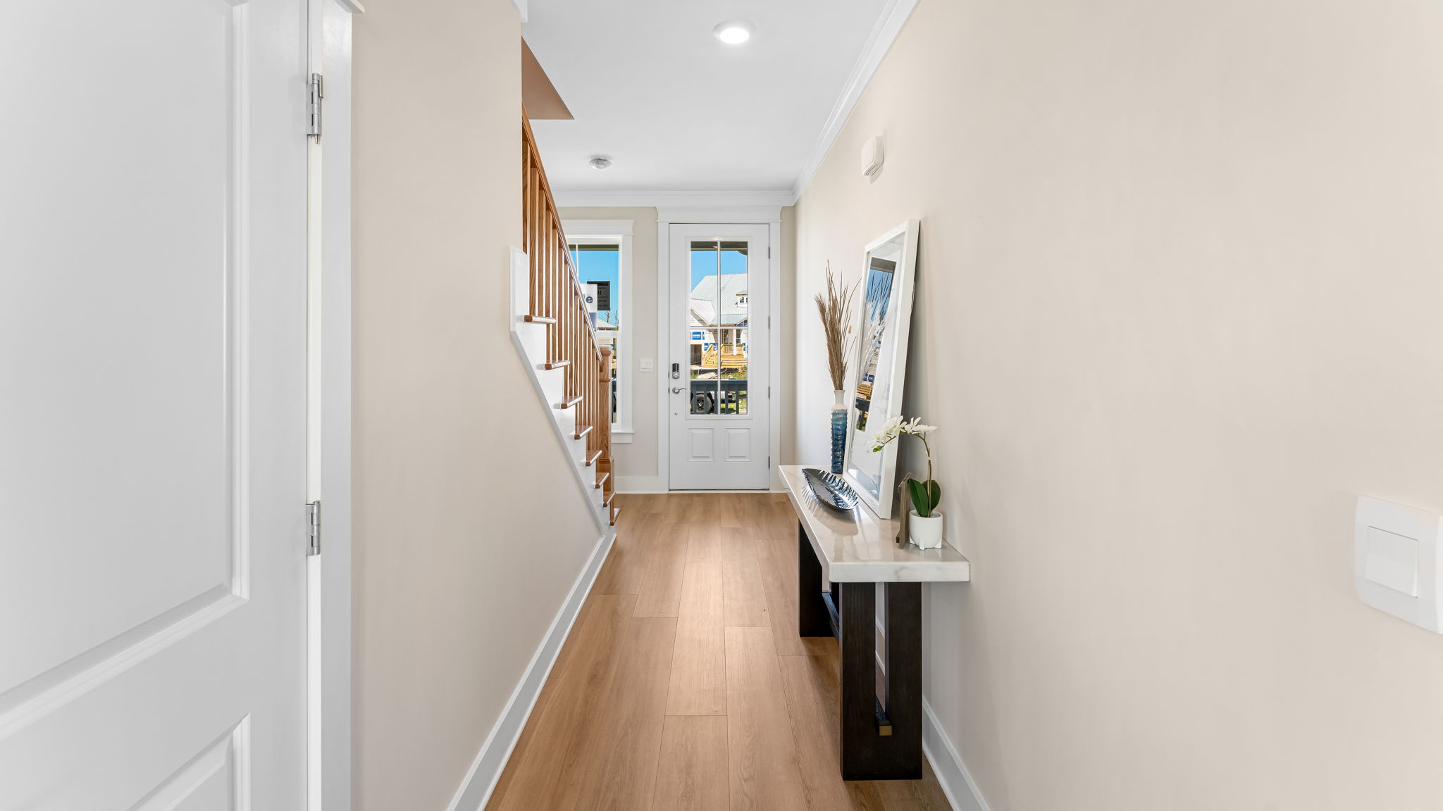 Front entrance hallway with EVP flooring next to wooden stairs and front door and windows.