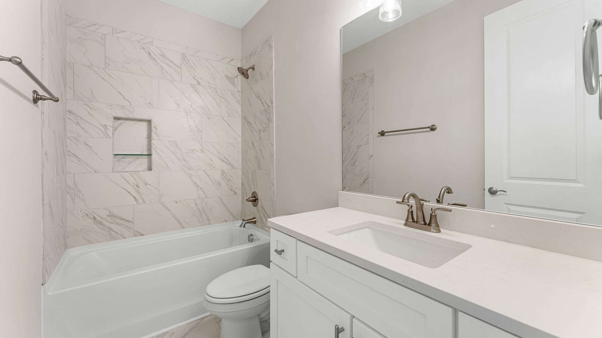 Bathroom with single vanity quartz countertops with white cabinets and Florentine tiled shower and tub combo.