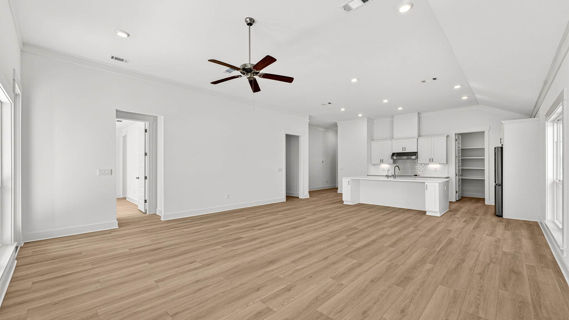Open living room with ceiling fan and EVP flooring and kitchen.