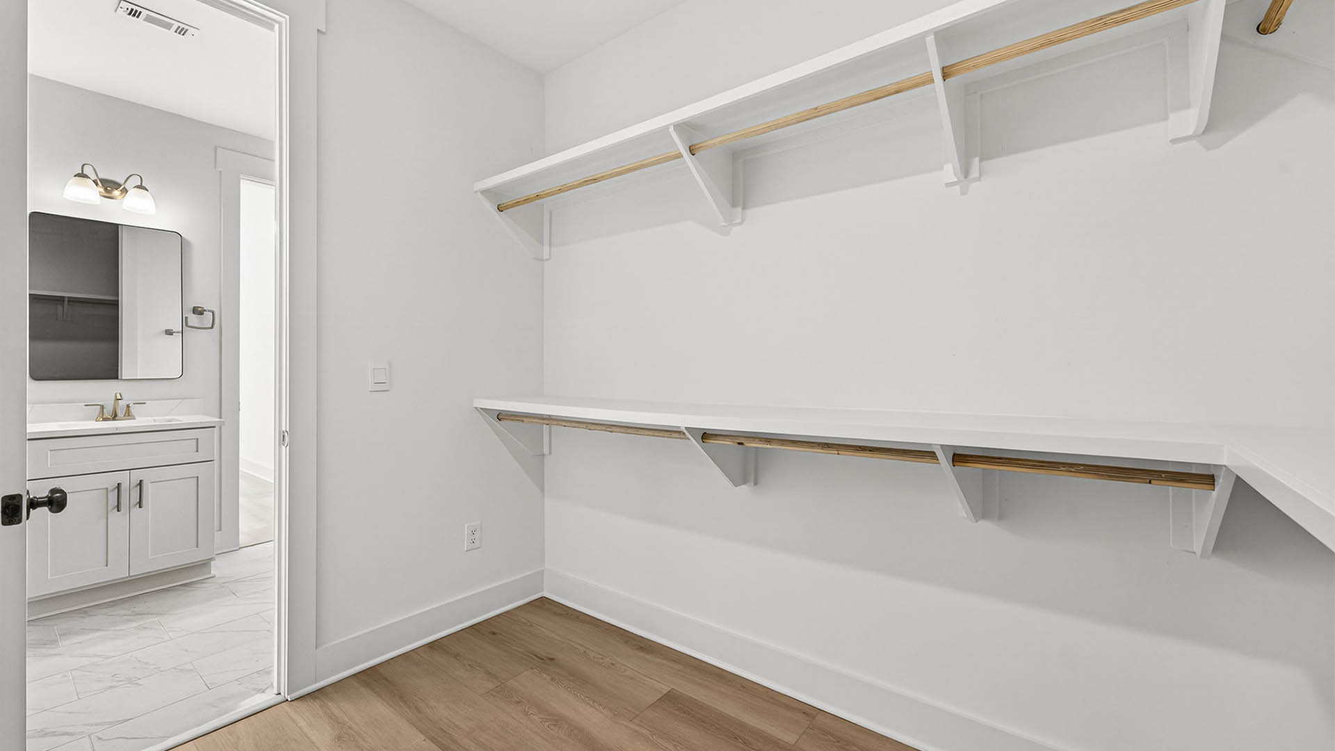 Primary bathroom closet with wooden shelving.