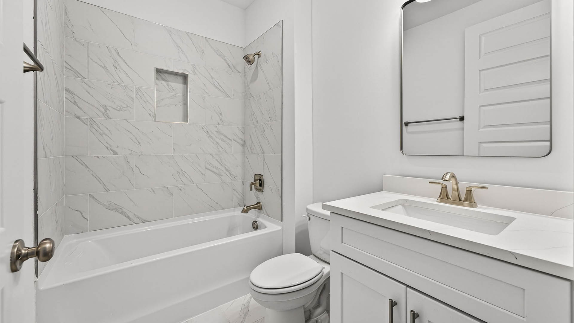 Bathroom with quartz countertop and tile shower and toilet and white cabinets.