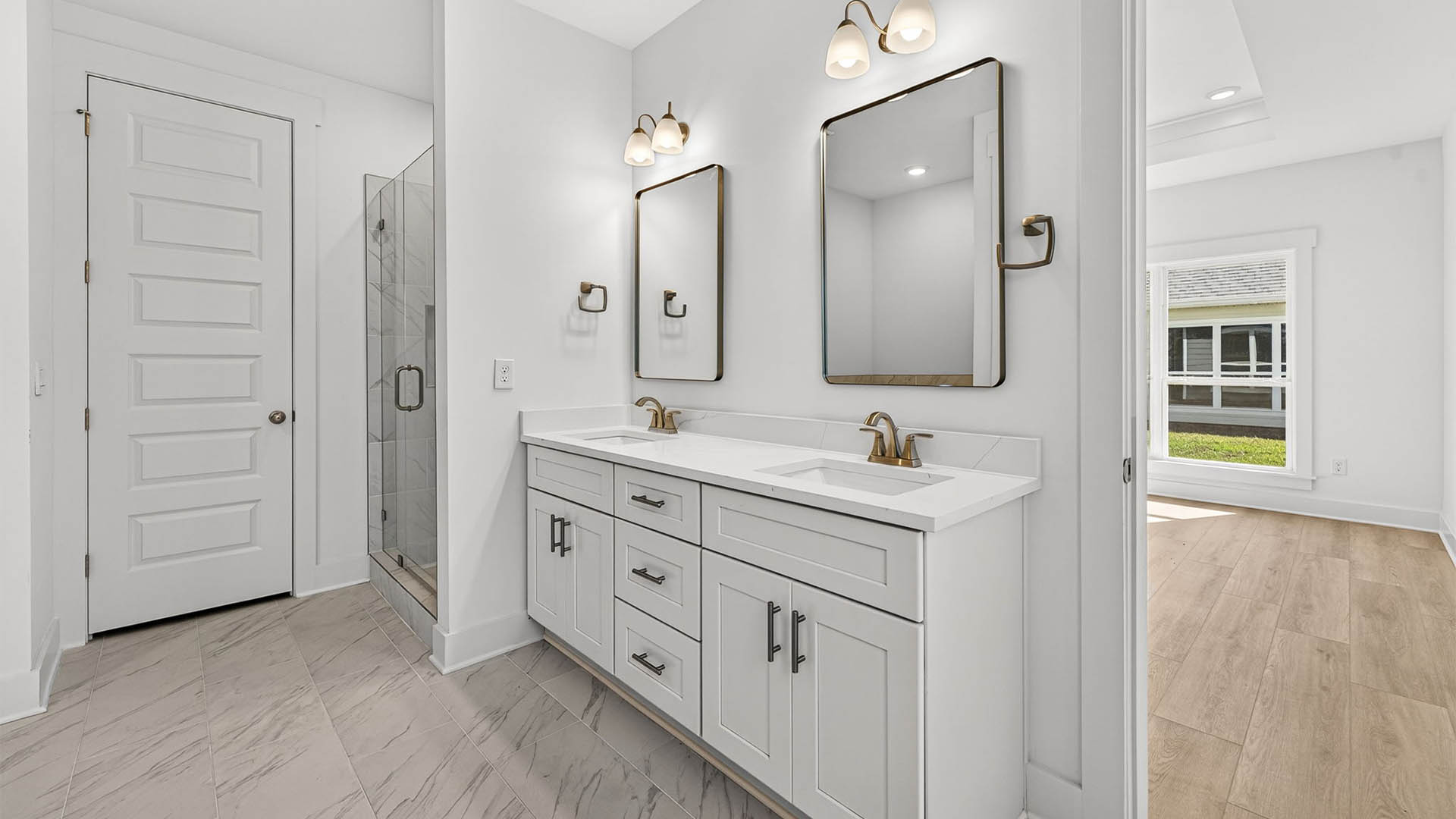 Primary bathroom with double vanity and quartz countertops and shower and closet.