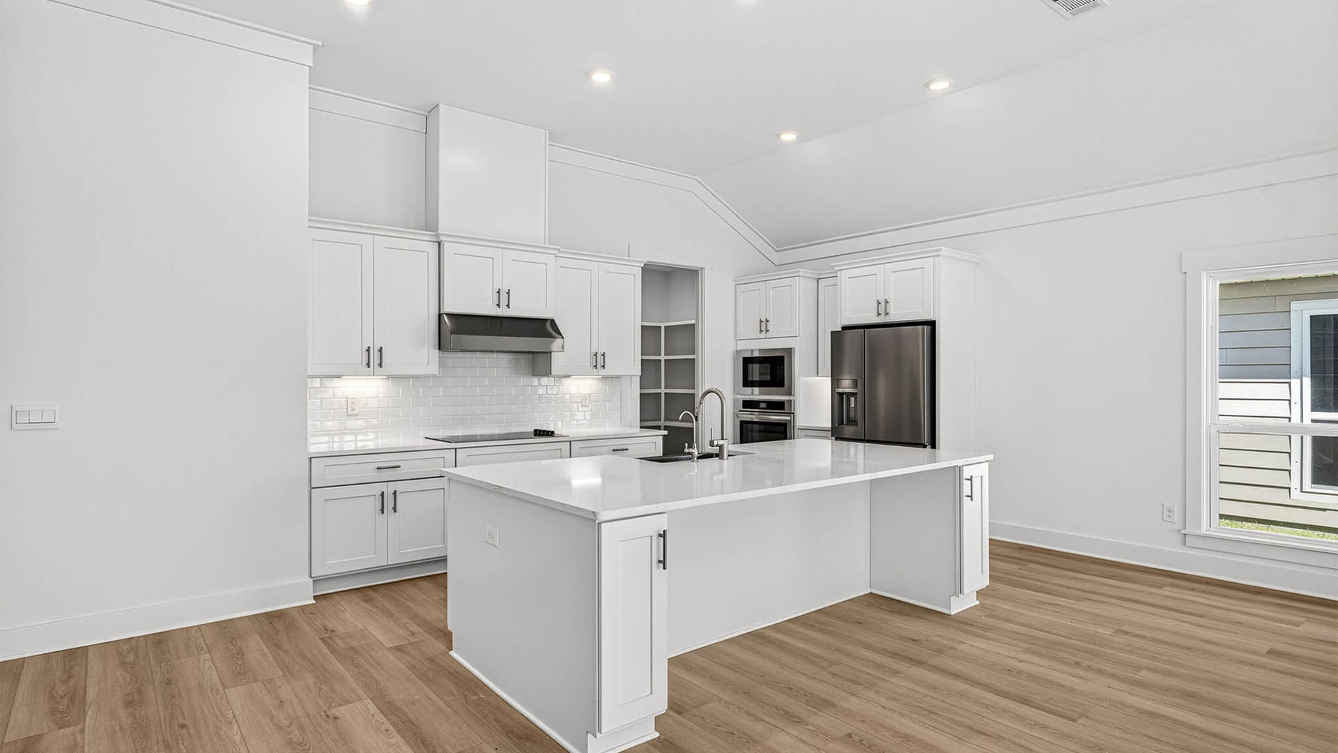 Kitchen with quartz countertops and backsplash and stainless-steel appliances and island.
