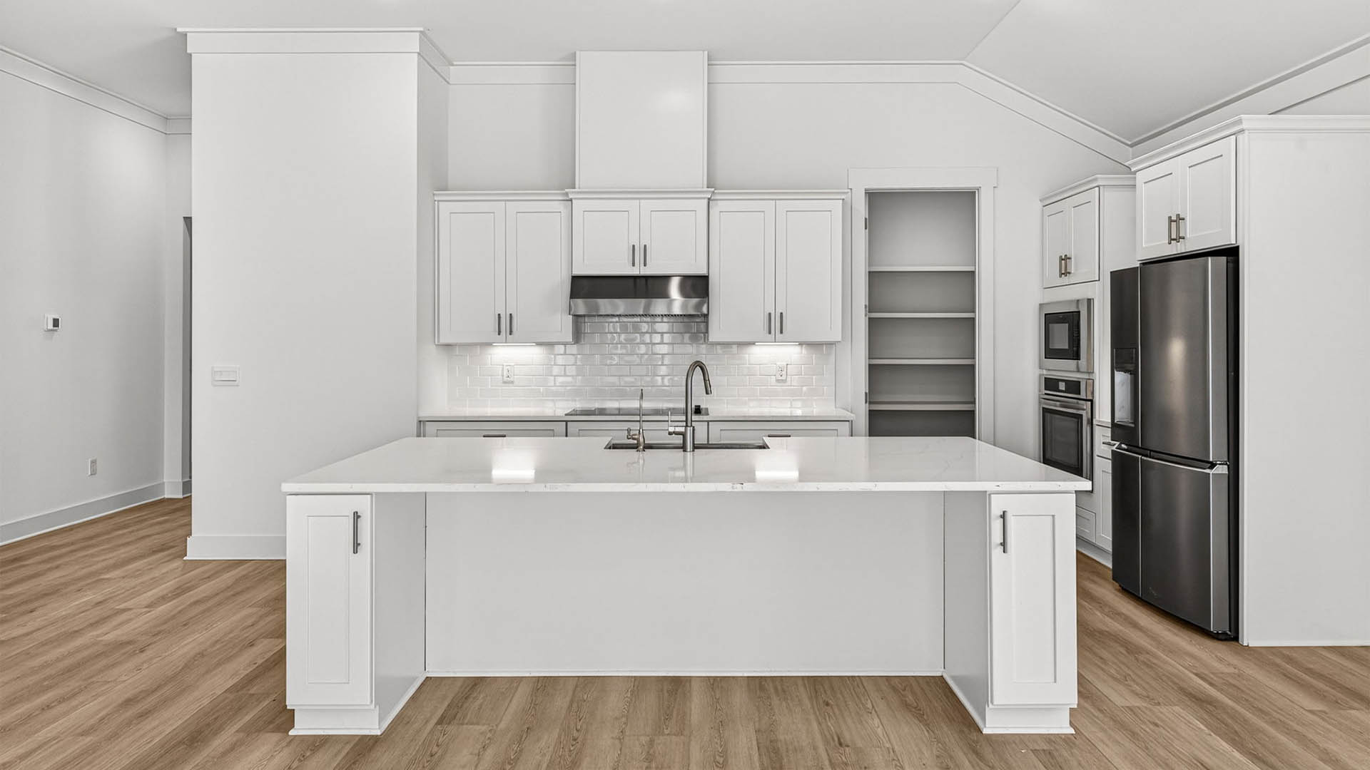 Kitchen with quartz countertops and backsplash and stainless-steel appliances and island.
