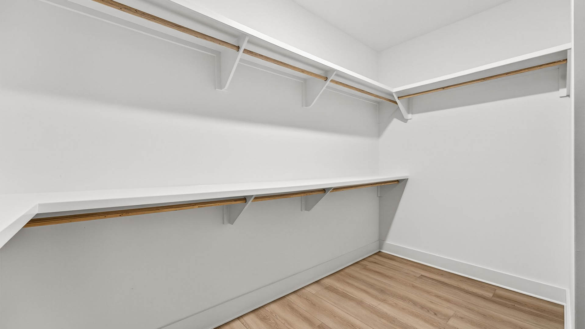 Primary bathroom closet with wooden shelving.