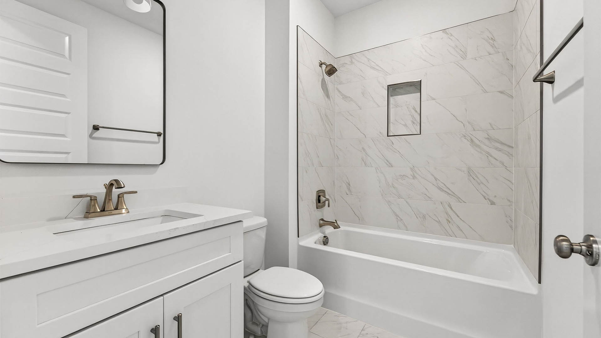 Bathroom with quartz countertop and tile shower and toilet and white cabinets.