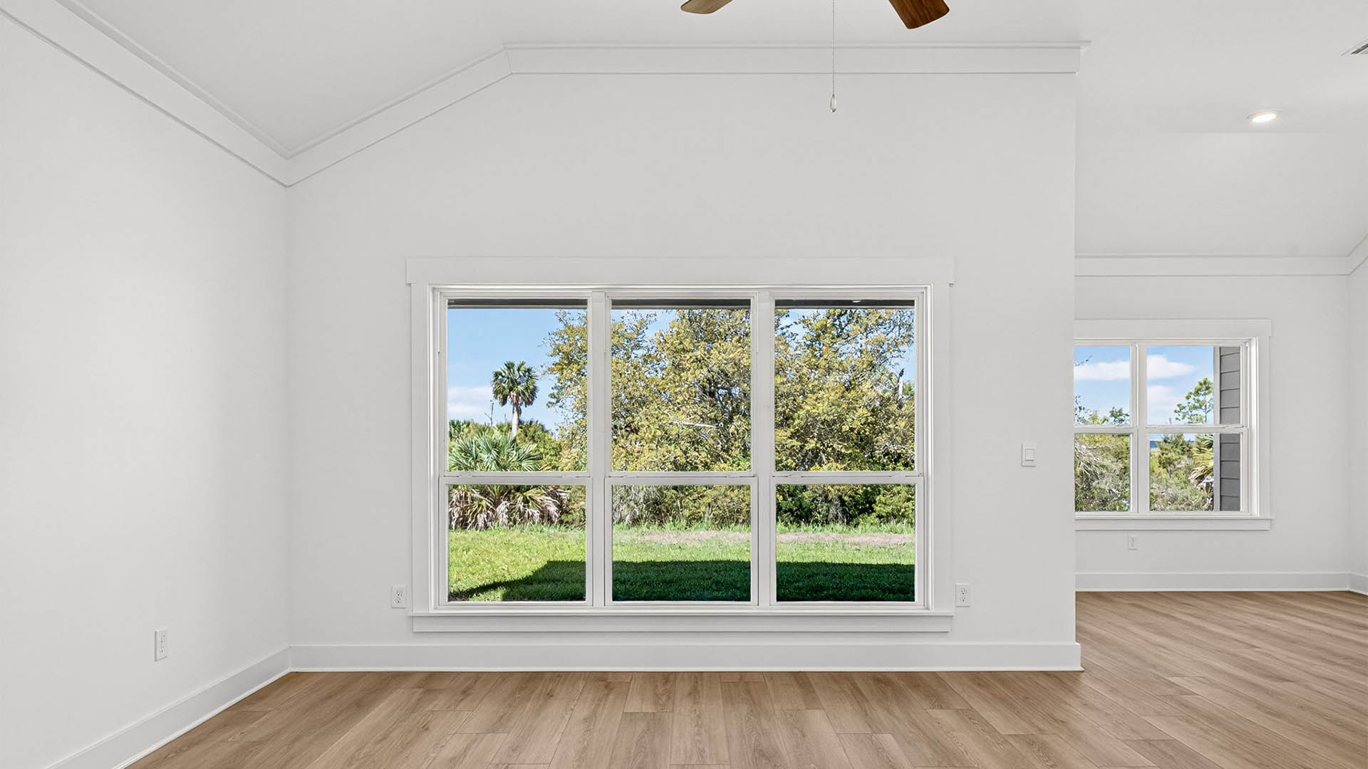 Open living room with ceiling fan and EVP flooring and windows.