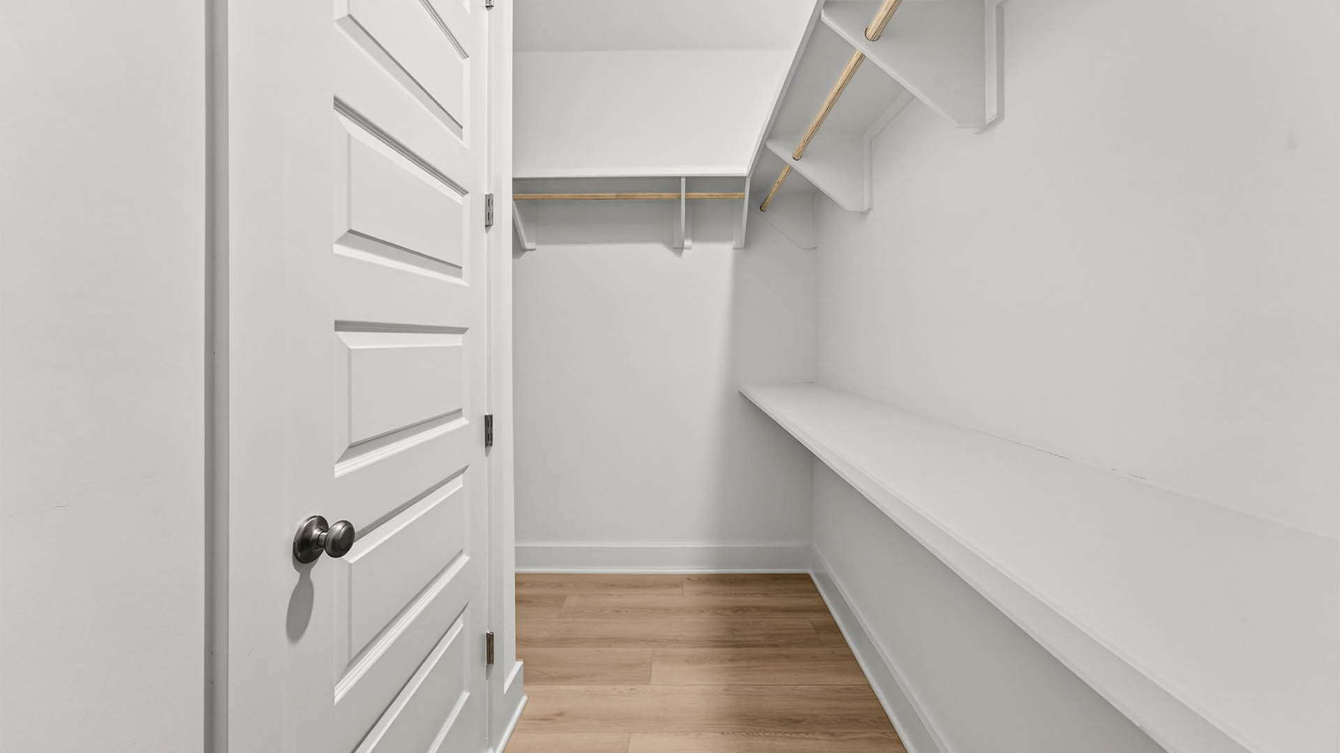 Primary bathroom closet with wooden shelving.