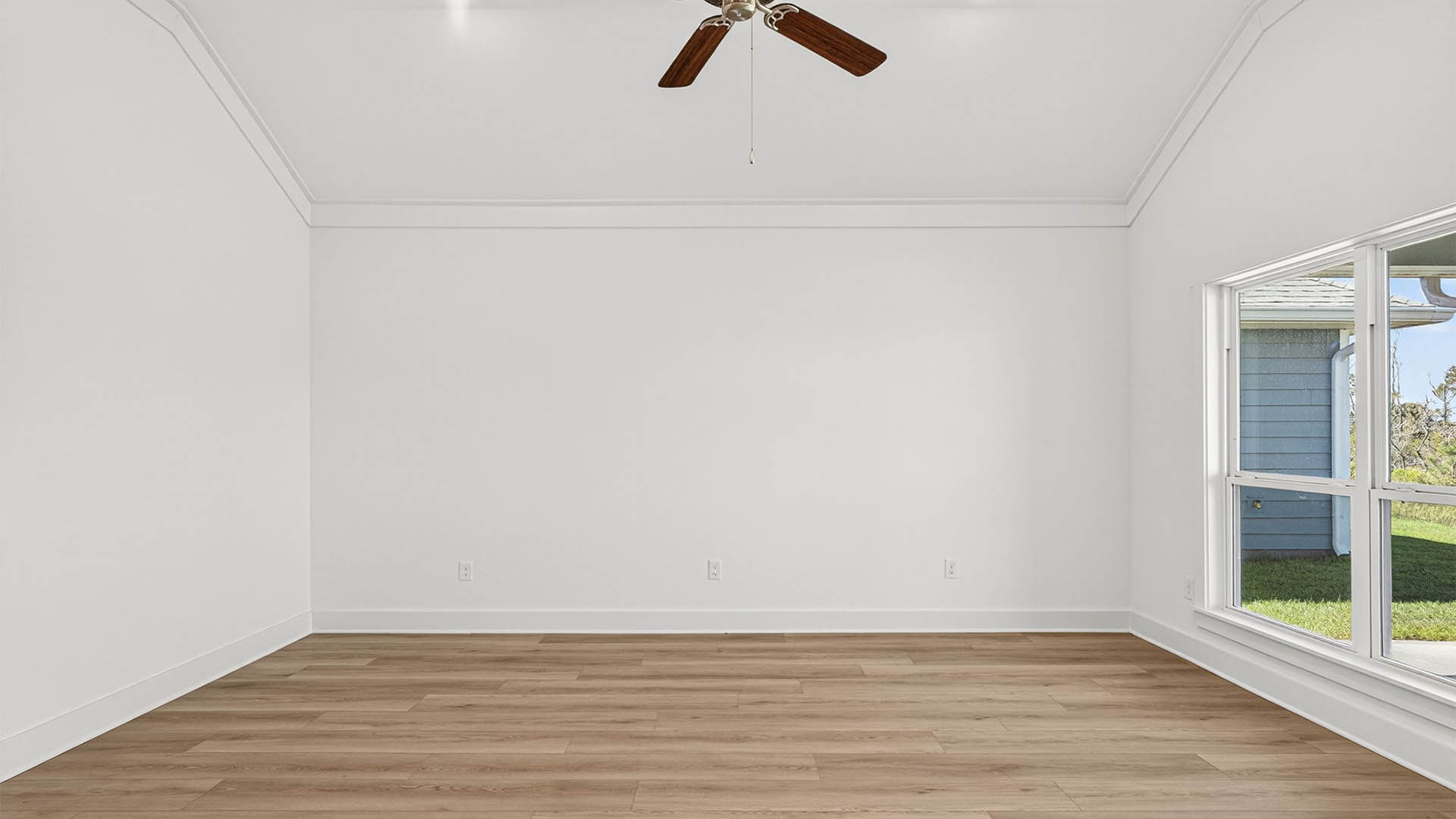 Open living room with ceiling fan and EVP flooring and windows.