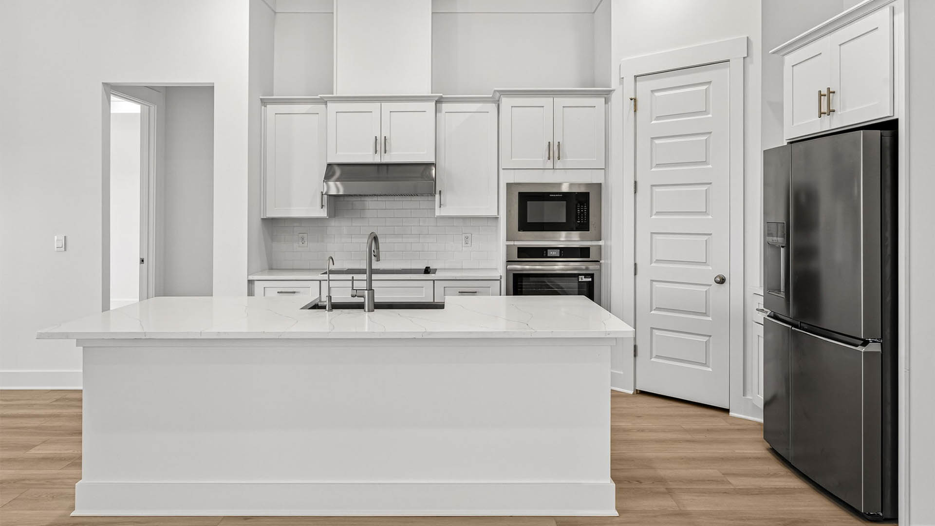 Kitchen with quartz countertops and backsplash and stainless-steel appliances and island.