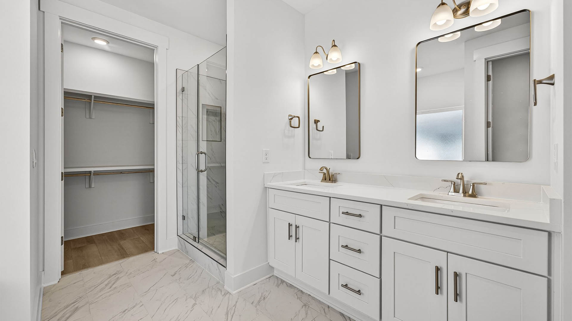 Primary bathroom with double vanity and quartz countertops and shower and closet.