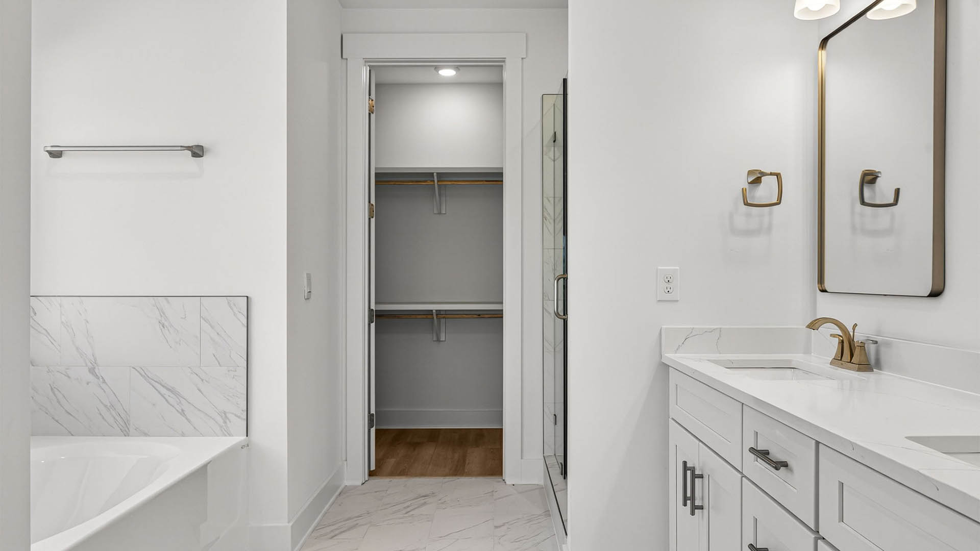 Primary bathroom with double vanity and quartz countertops and shower and closet.
