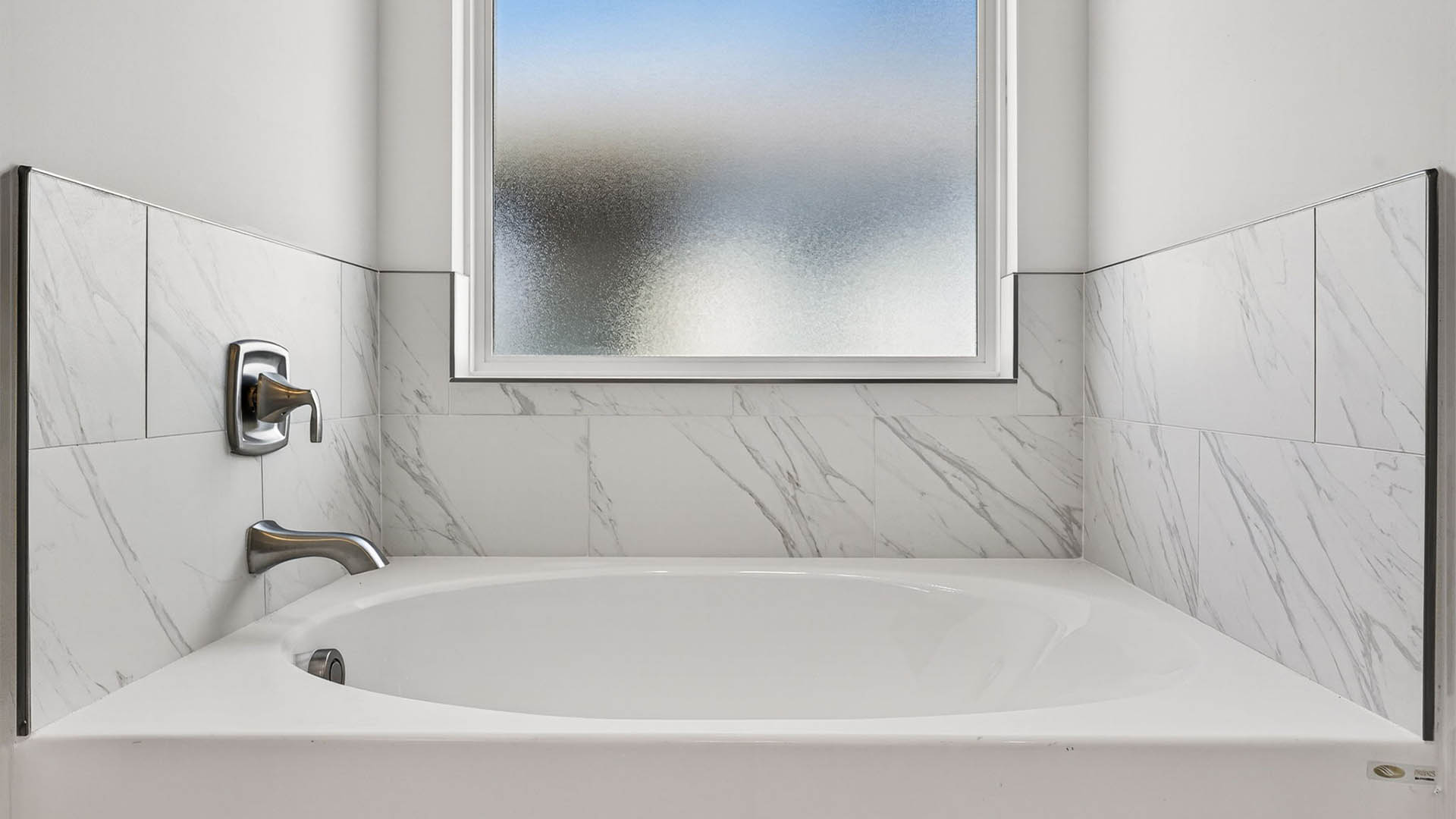 Tub with tile backsplash and frosted glass window.
