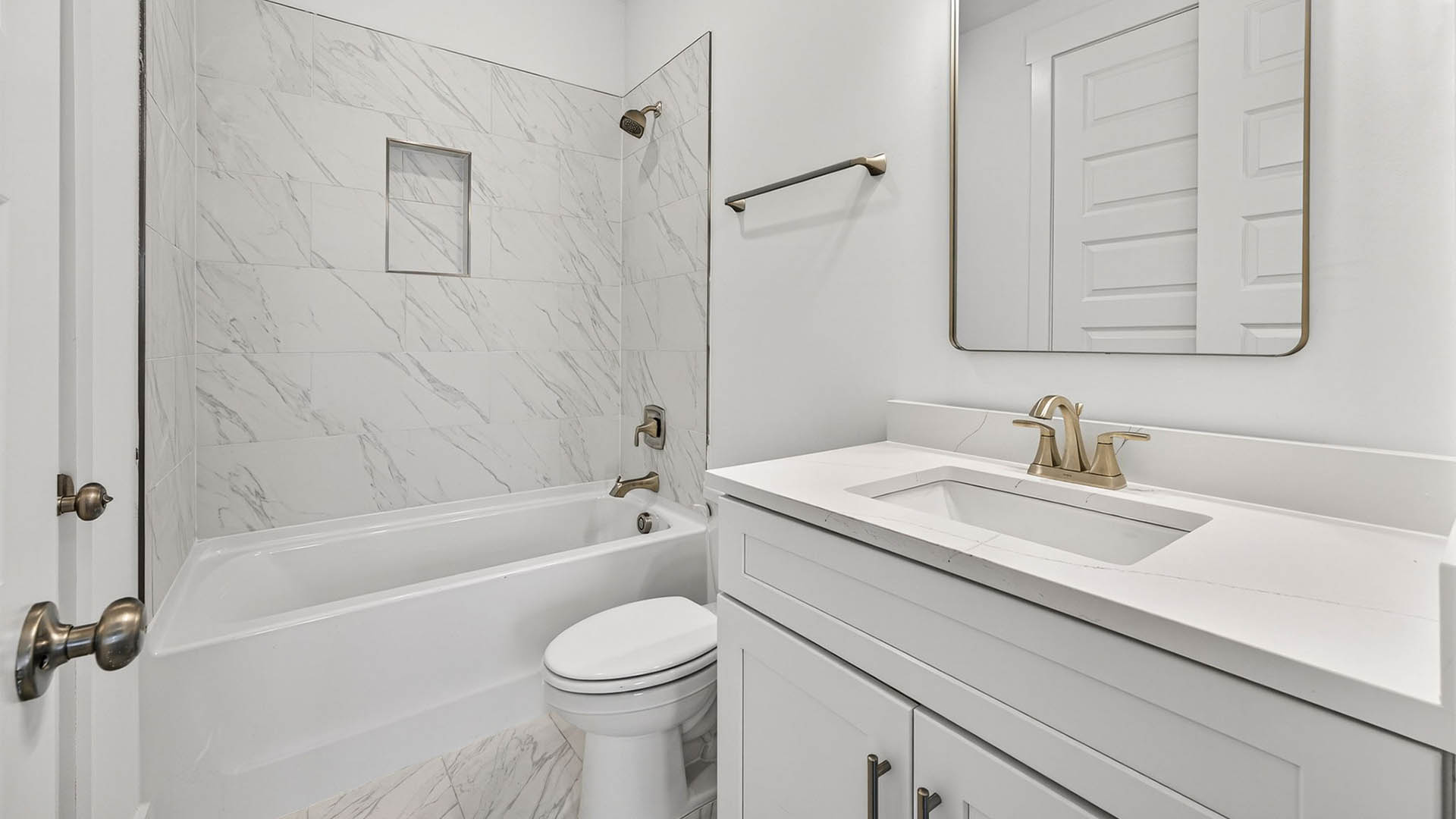 Bathroom with quartz countertop and tile shower and toilet and white cabinets.