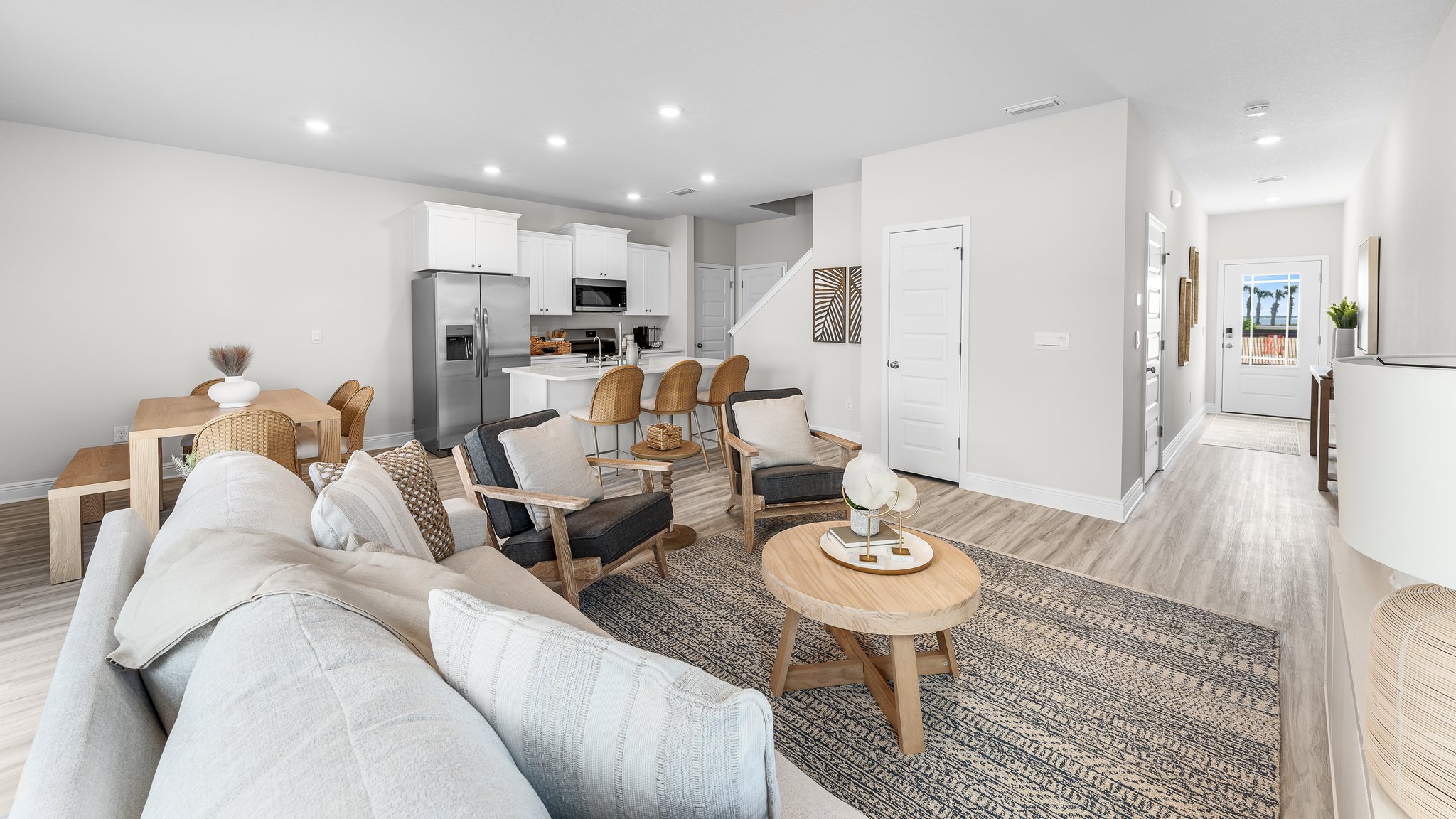 Open living room with EVP flooring and kitchen and windows.