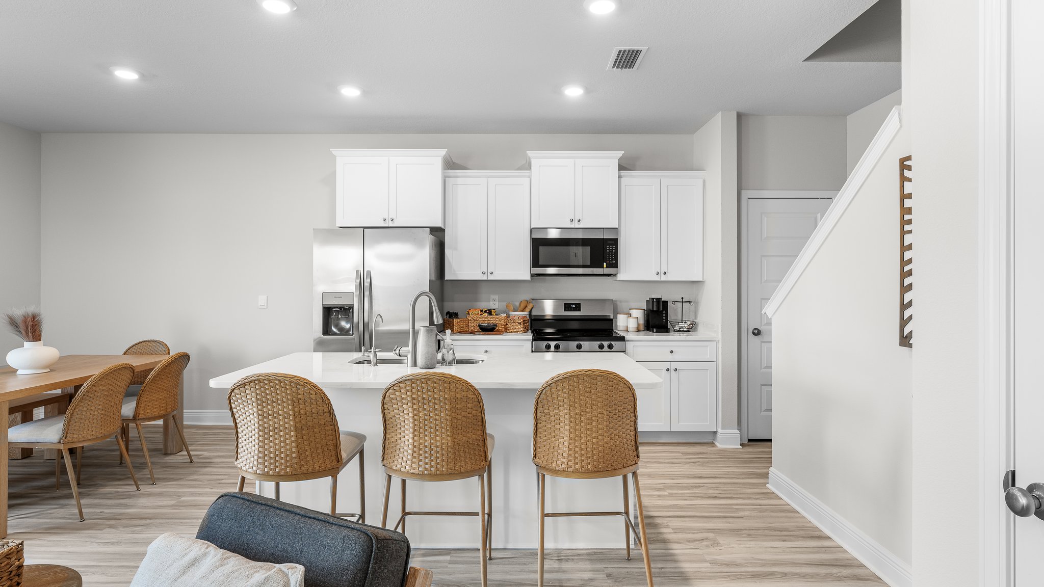 Kitchen with island and quartz countertops and stainless steel appliances and white cabinets.