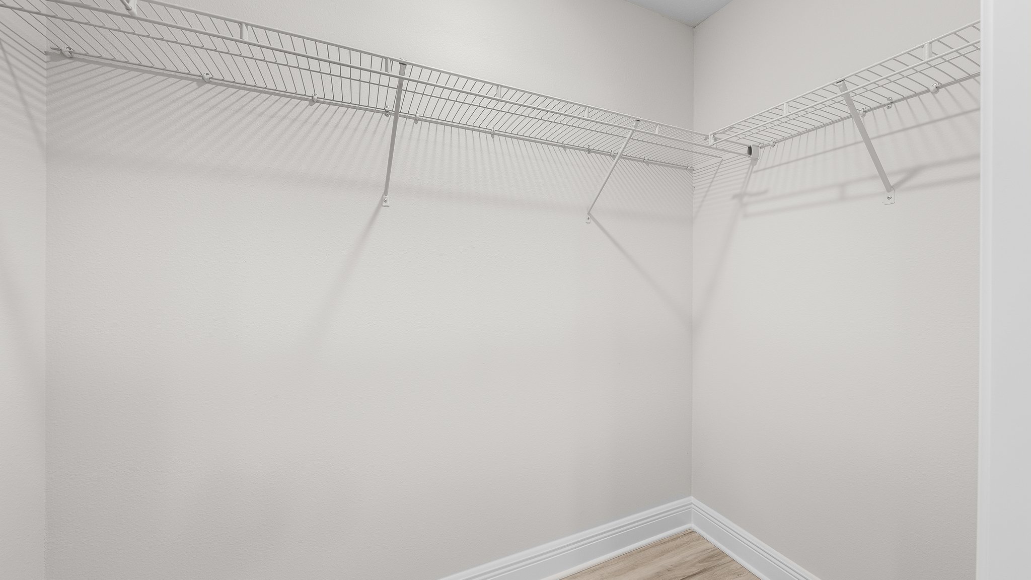Primary bathroom closet with EVP flooring and ventilated shelving.