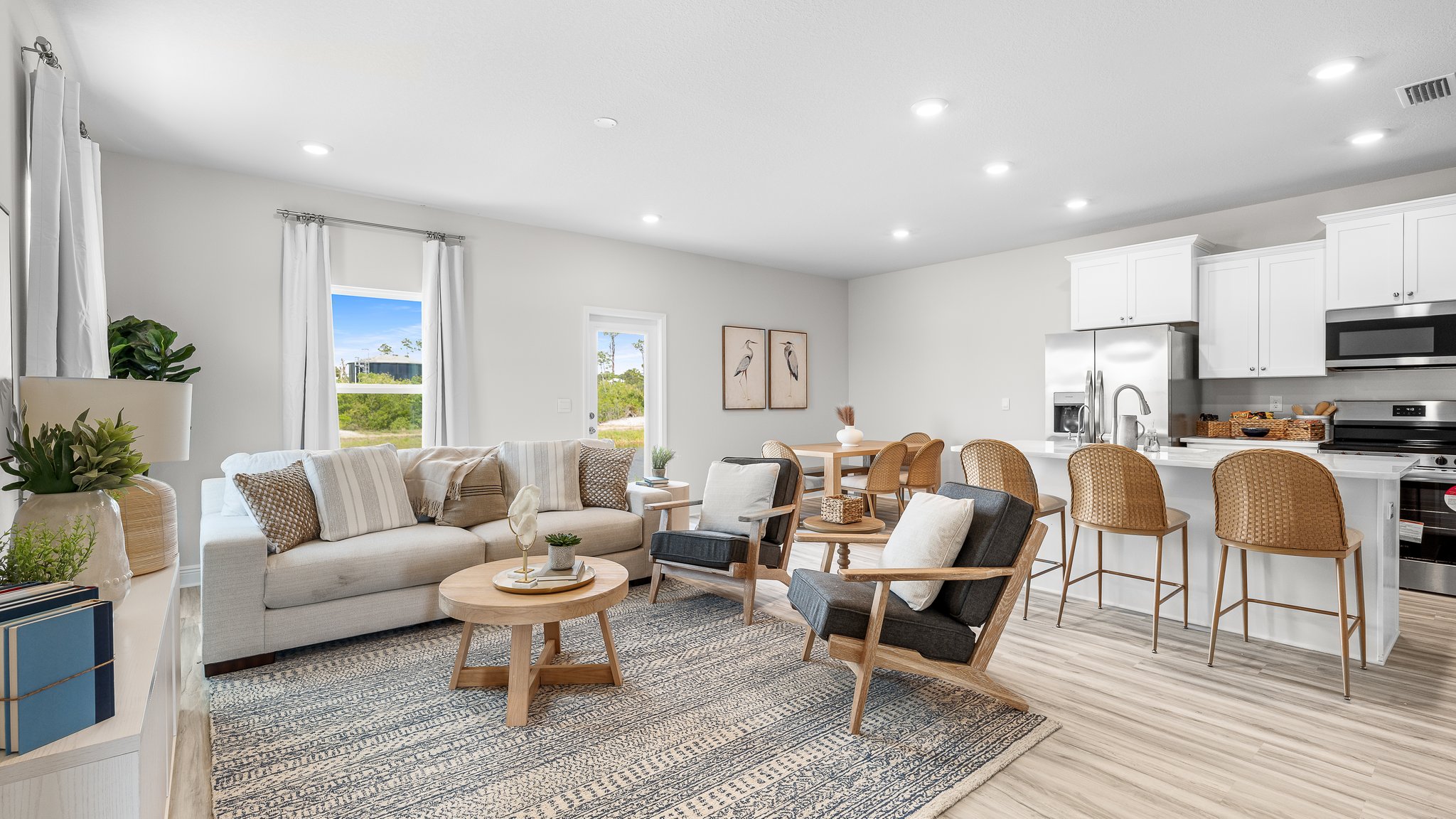 Open living room with EVP flooring and kitchen and windows.