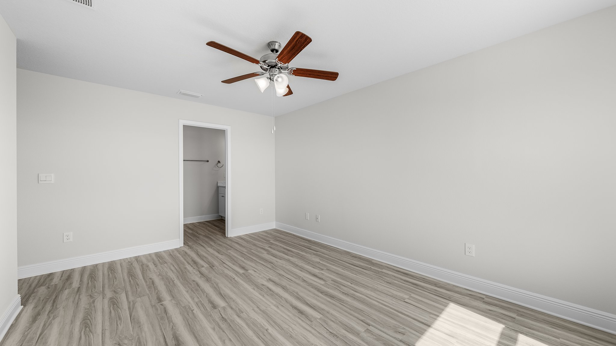 Primary Bedroom with EVP flooring and ceiling fan and bathroom entrance.