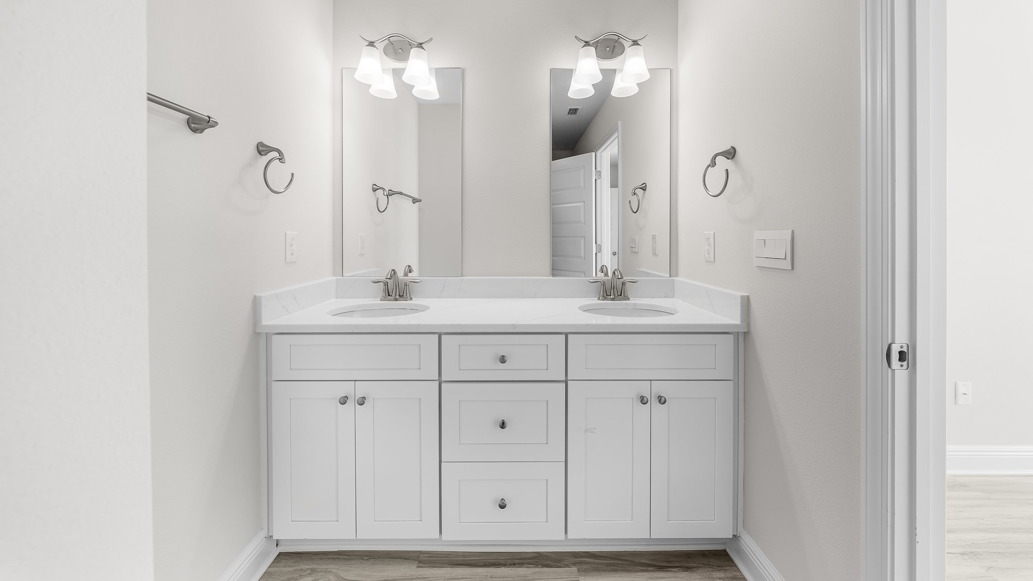 Primary bathroom with double vanity quartz countertops with white cabinets and EVP flooring.