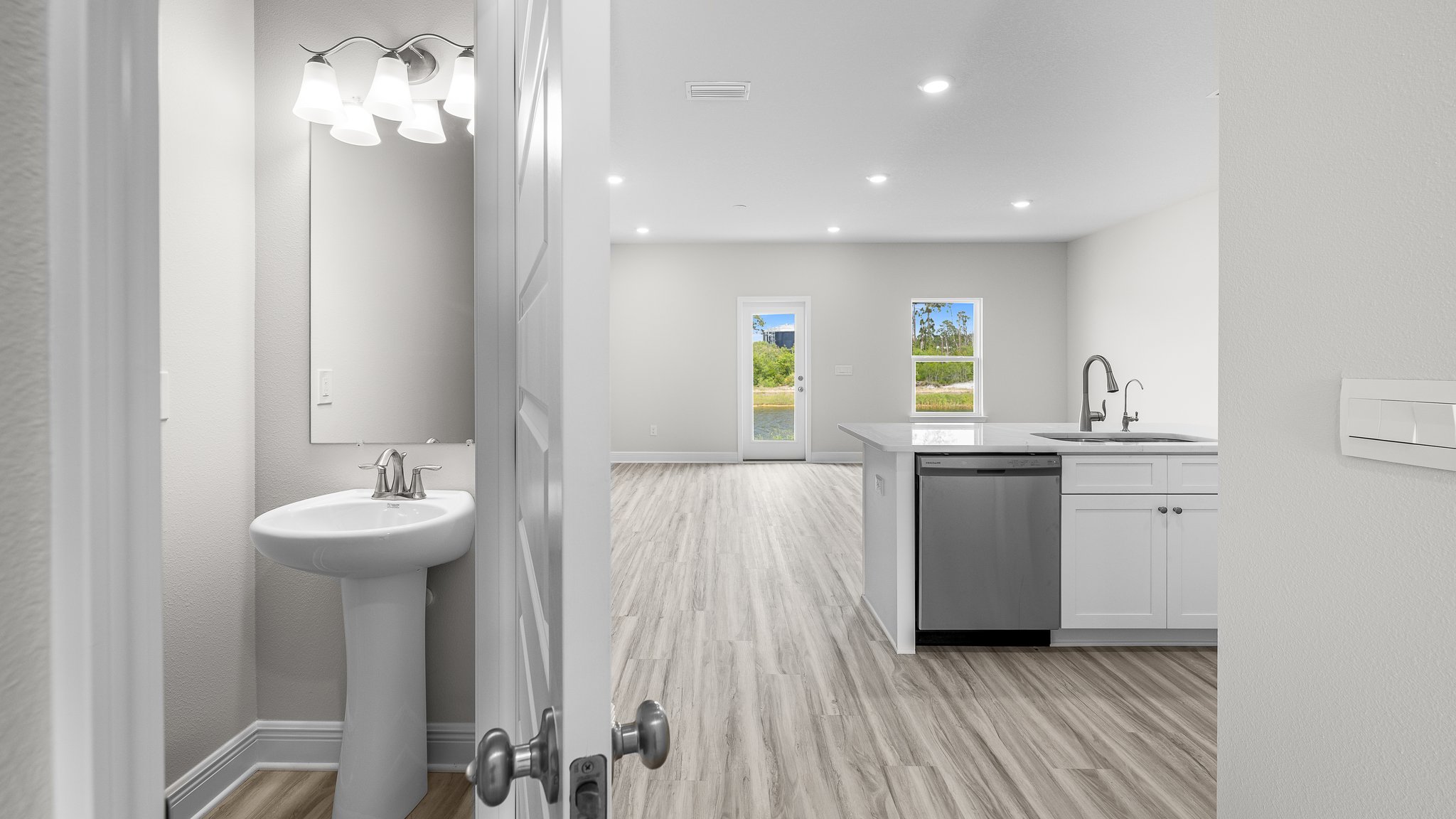 Hallway with half bathroom next to kitchen.