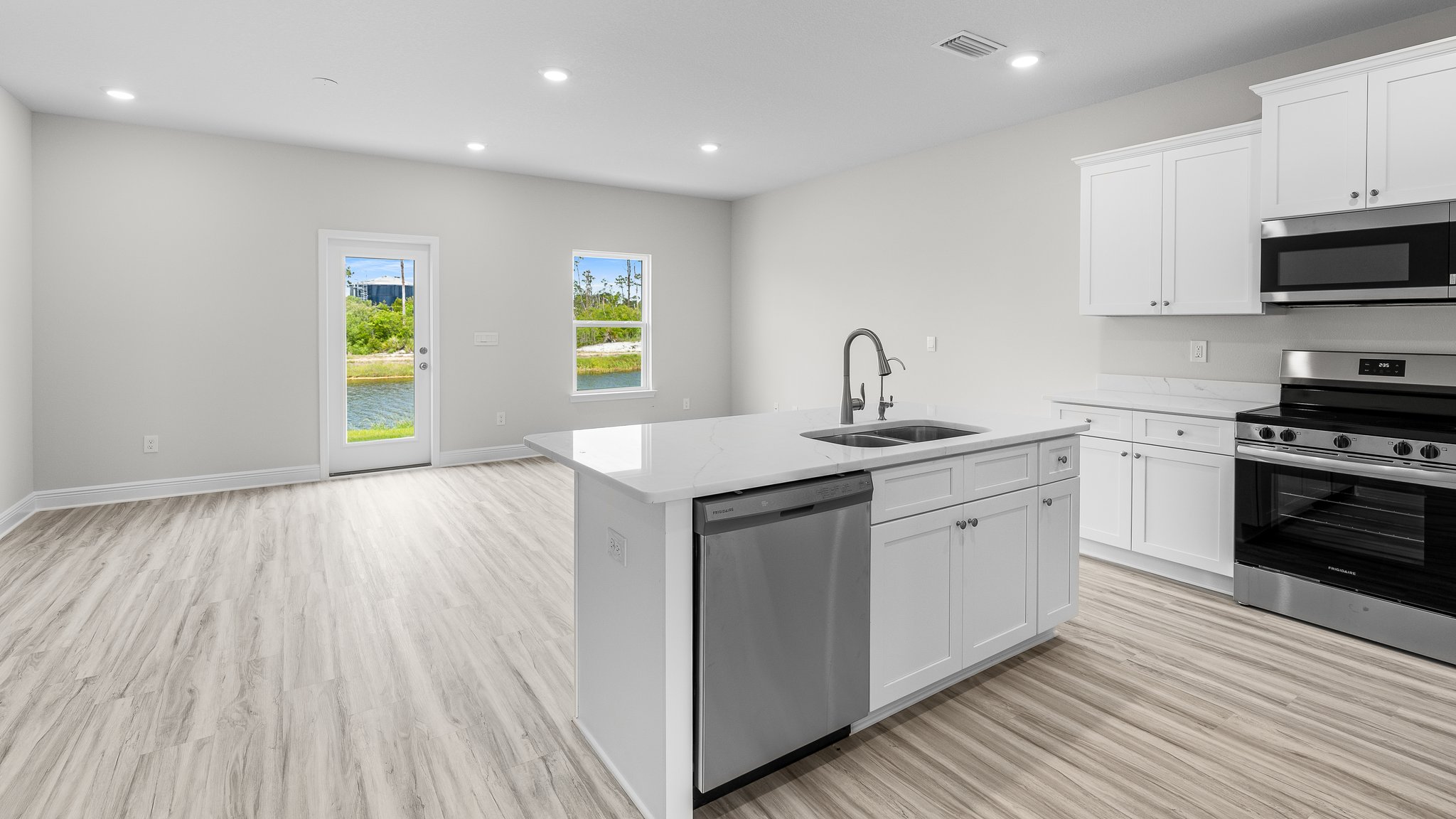 Open kitchen and living room with EVP flooring and back door.