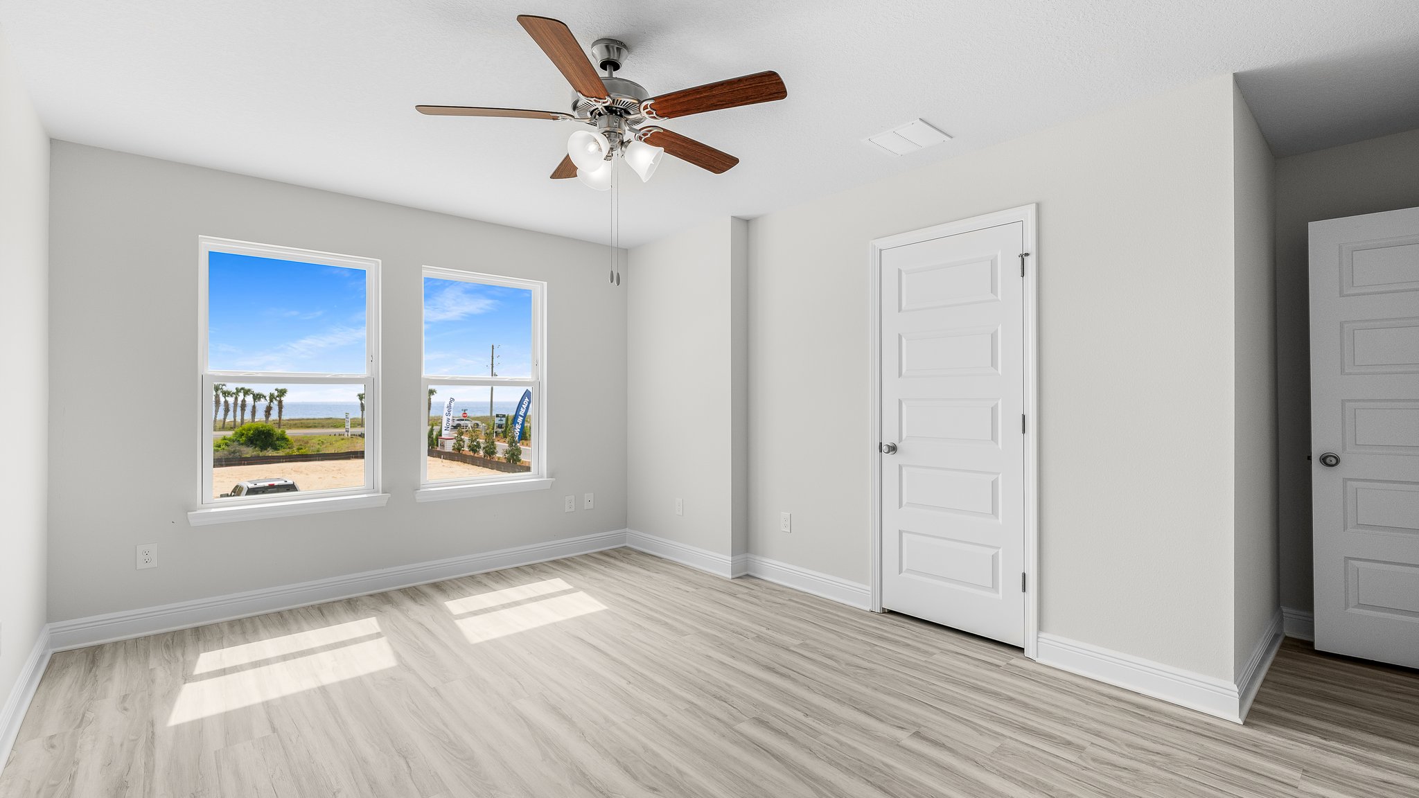 Primary Bedroom with EVP flooring and ceiling fan and two windows.