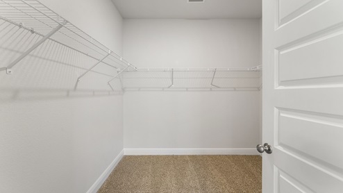 Master bathroom walk in closet with ventilated shelving.