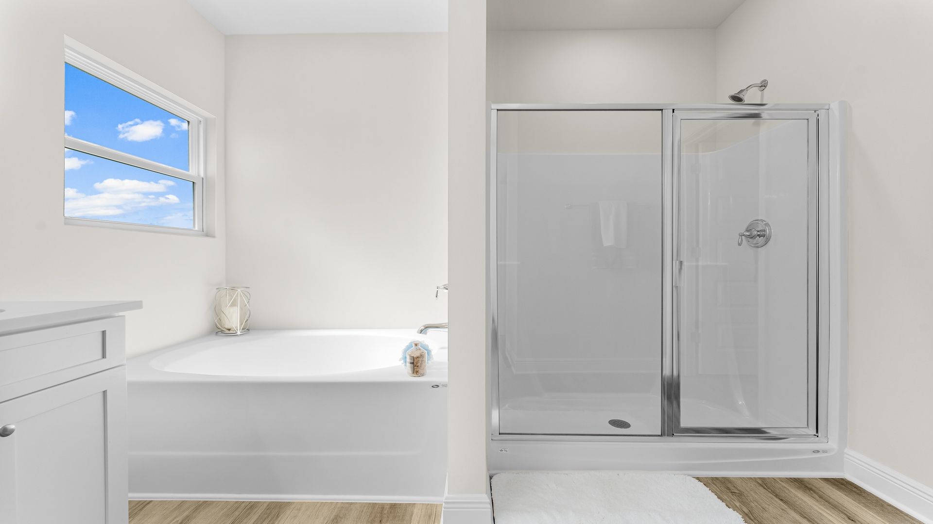 Primary bathroom tub and walk-in shower with glass doors.