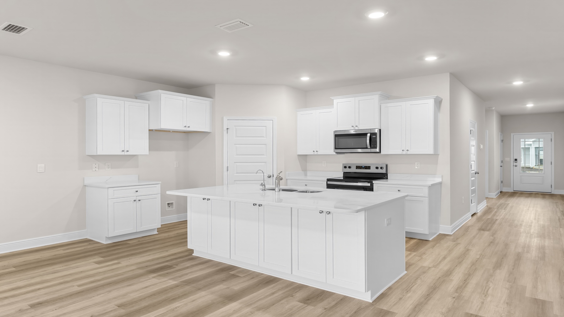 Kitchen with large island with white cabinets and quartz countertops and stainless-steel appliances and walk-in pantry.