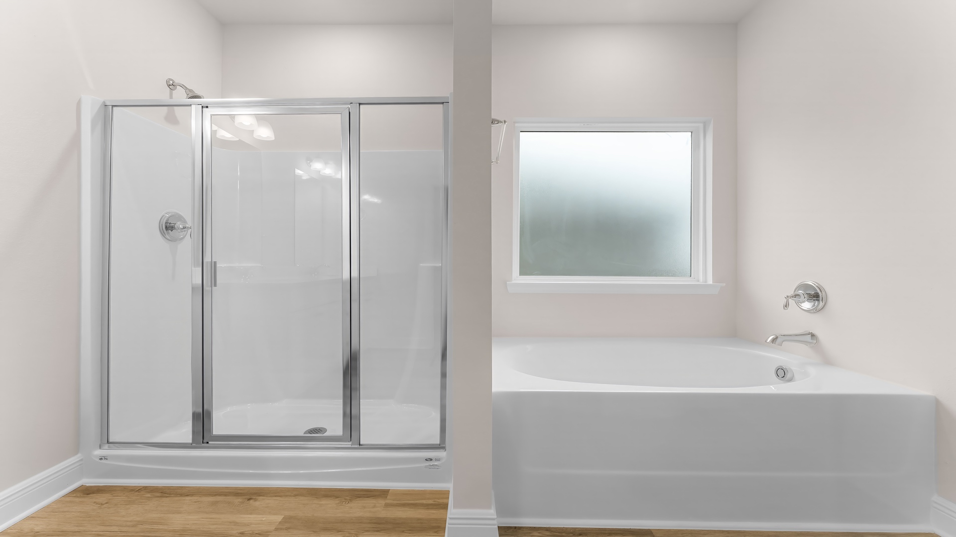 Primary bathroom shower with glass doors and tub with opaque glass window.