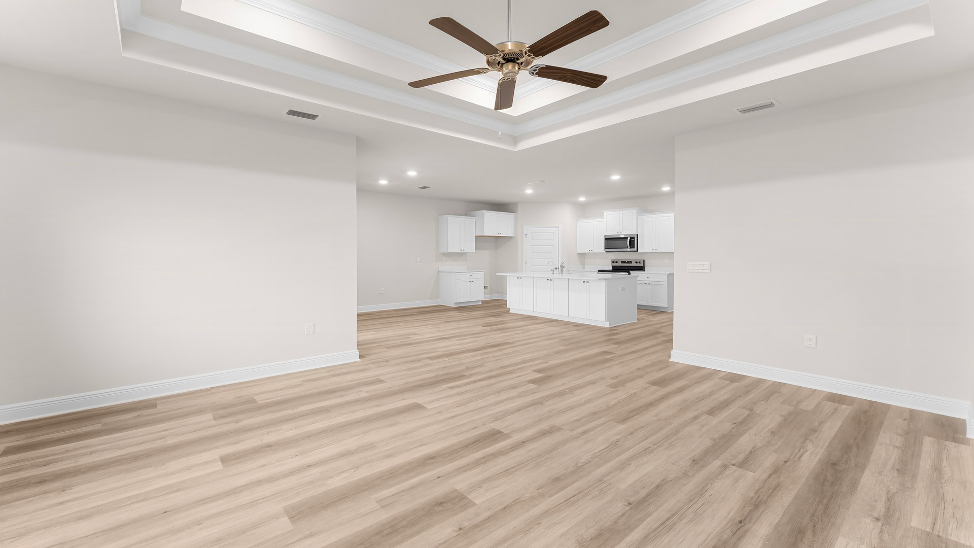 Living room with tray ceilings and ceiling fan and EVP flooring and kitchen.