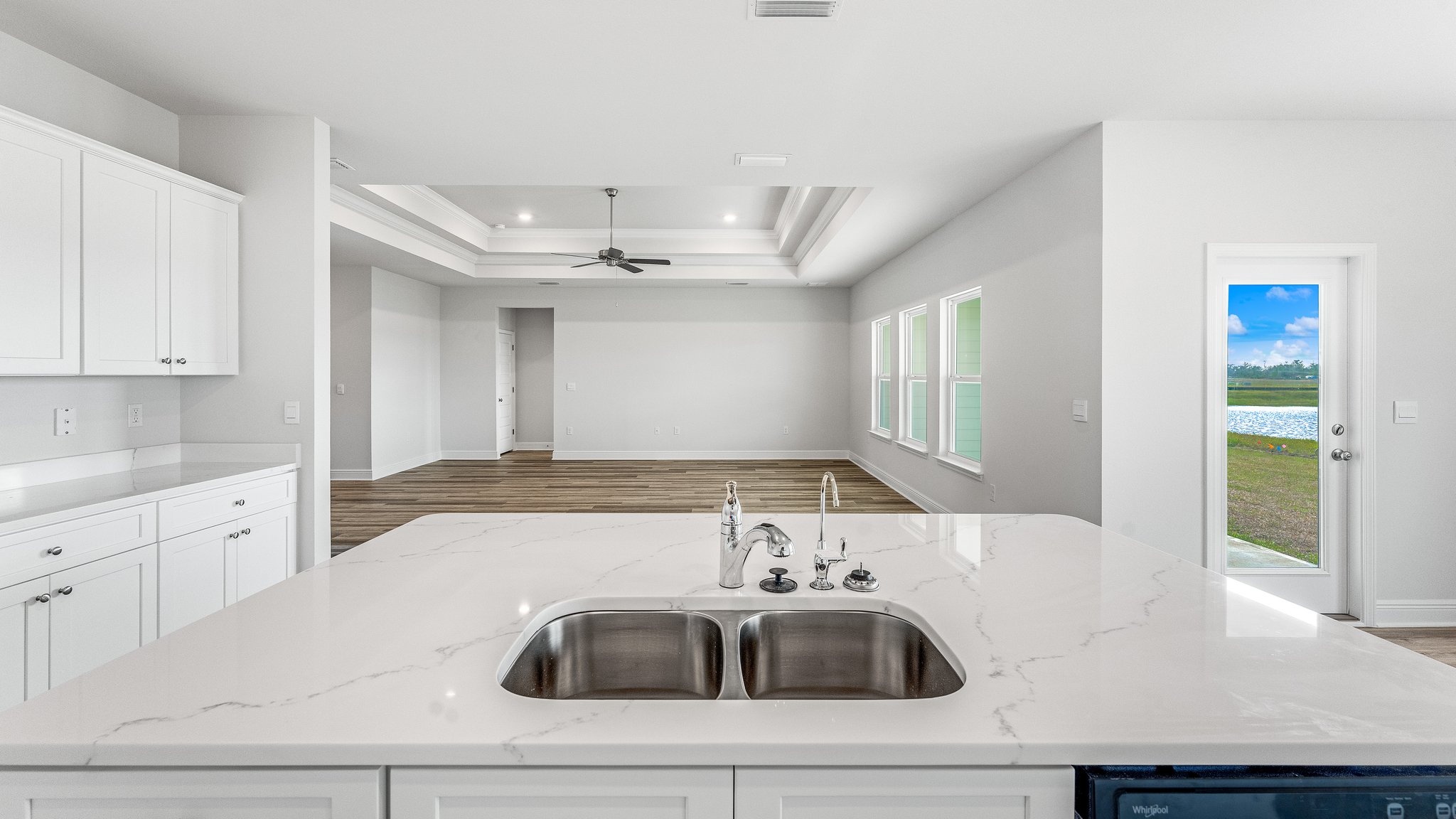 Kitchen island with white cabinets and quartz countertops and under mount sink.