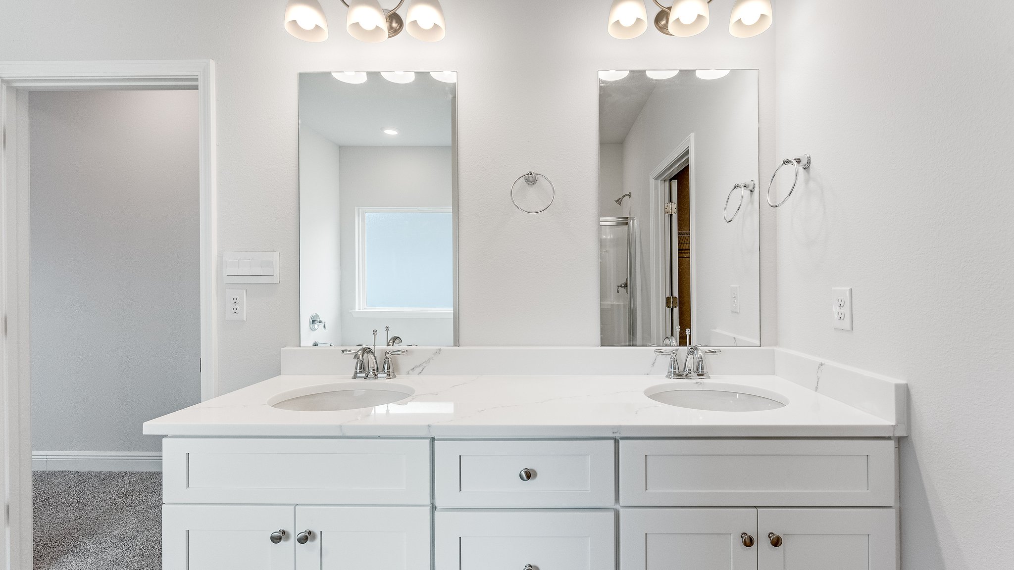 Primary bathroom white cabinets and double vanity with quartz countertops.