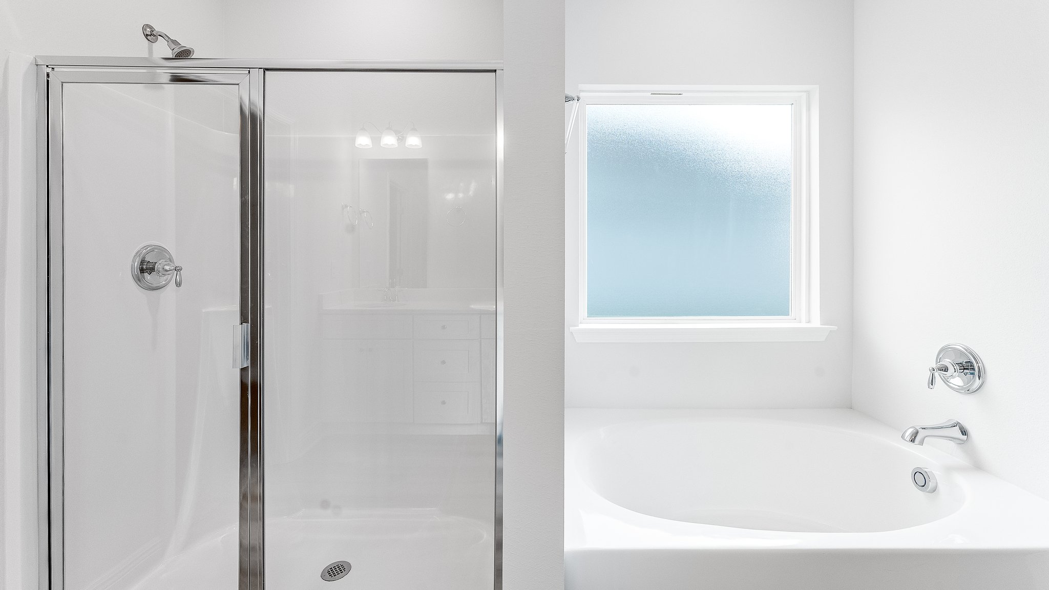 Primary bathroom walk-in shower with glass doors and tub with window.