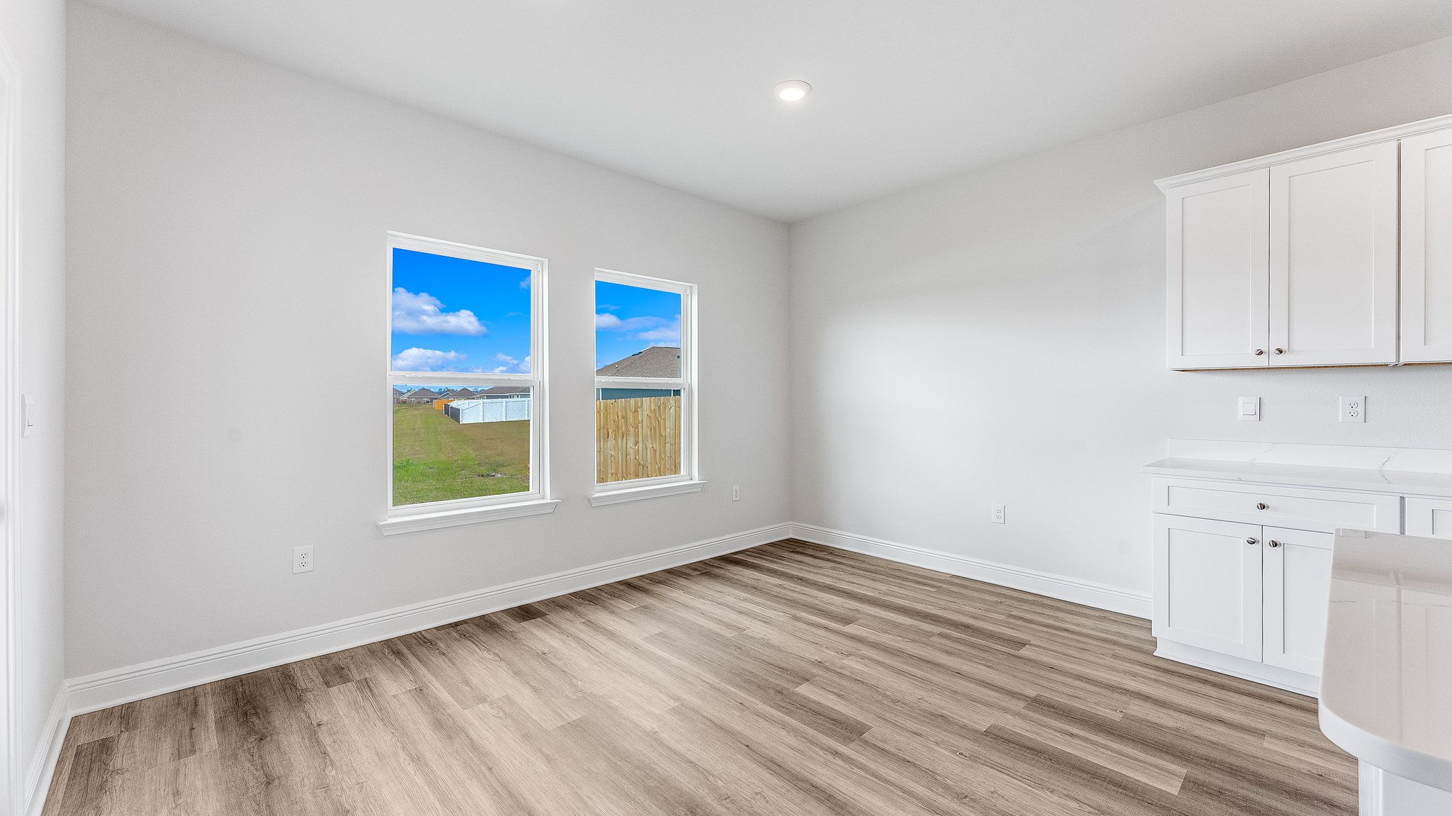 Dining area next to back door and kitchen with two windows.