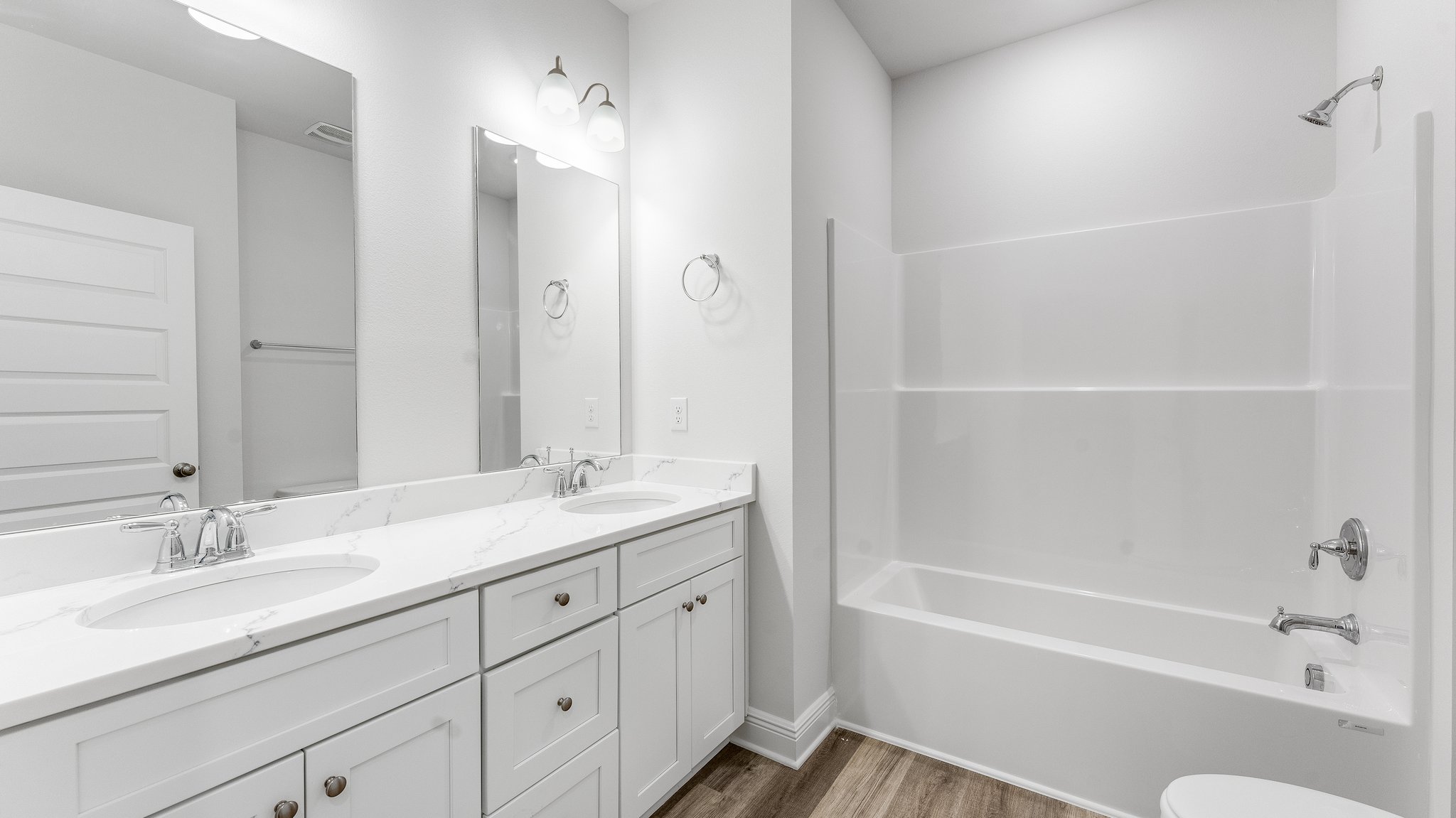 Bathroom with double vanity quartz countertops with white cabinets and tub and shower and toilet.