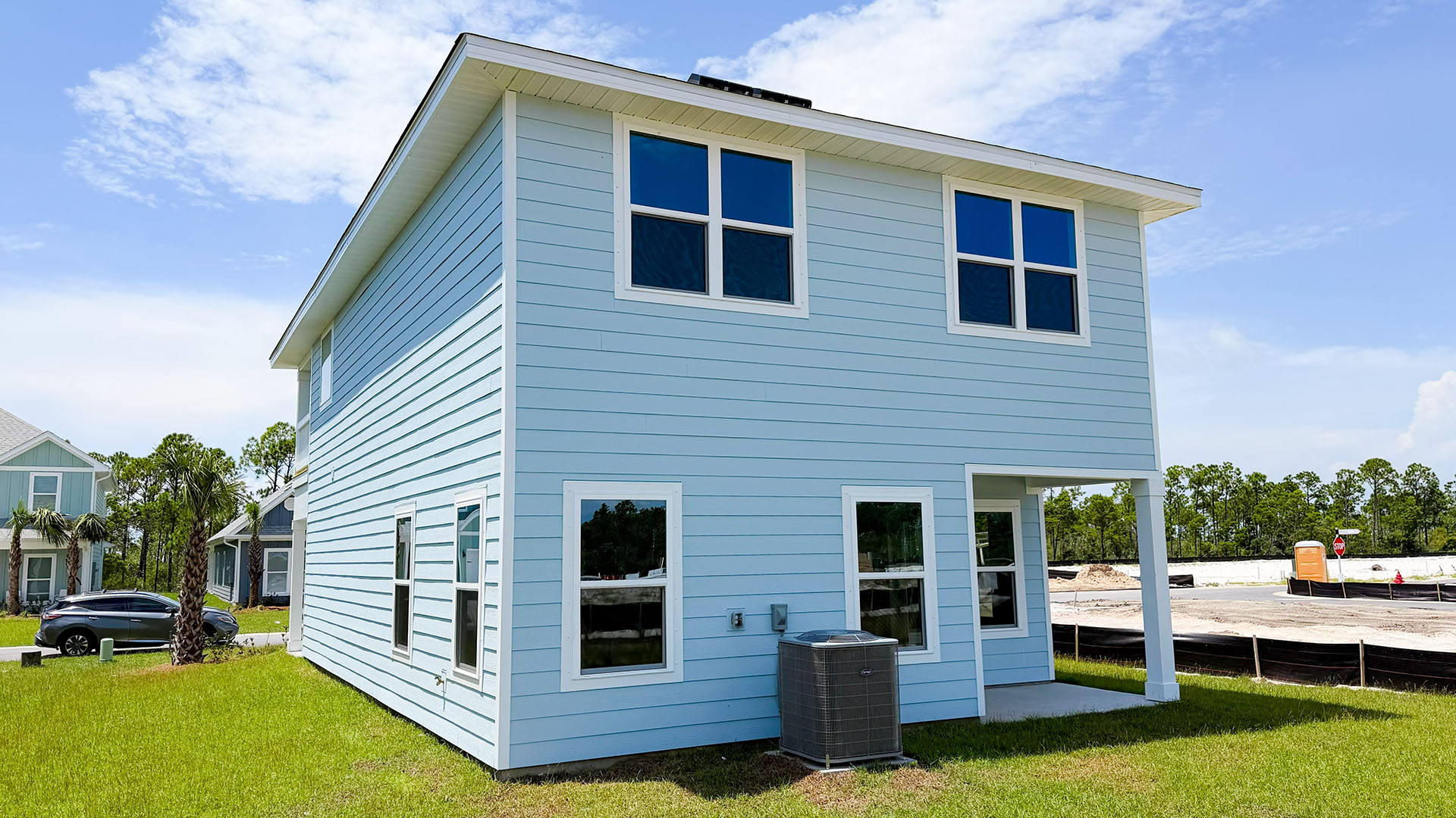Monroe floor plan at WindMark Beach with Hardie siding and covered front porch and balcony and 1 car garage.