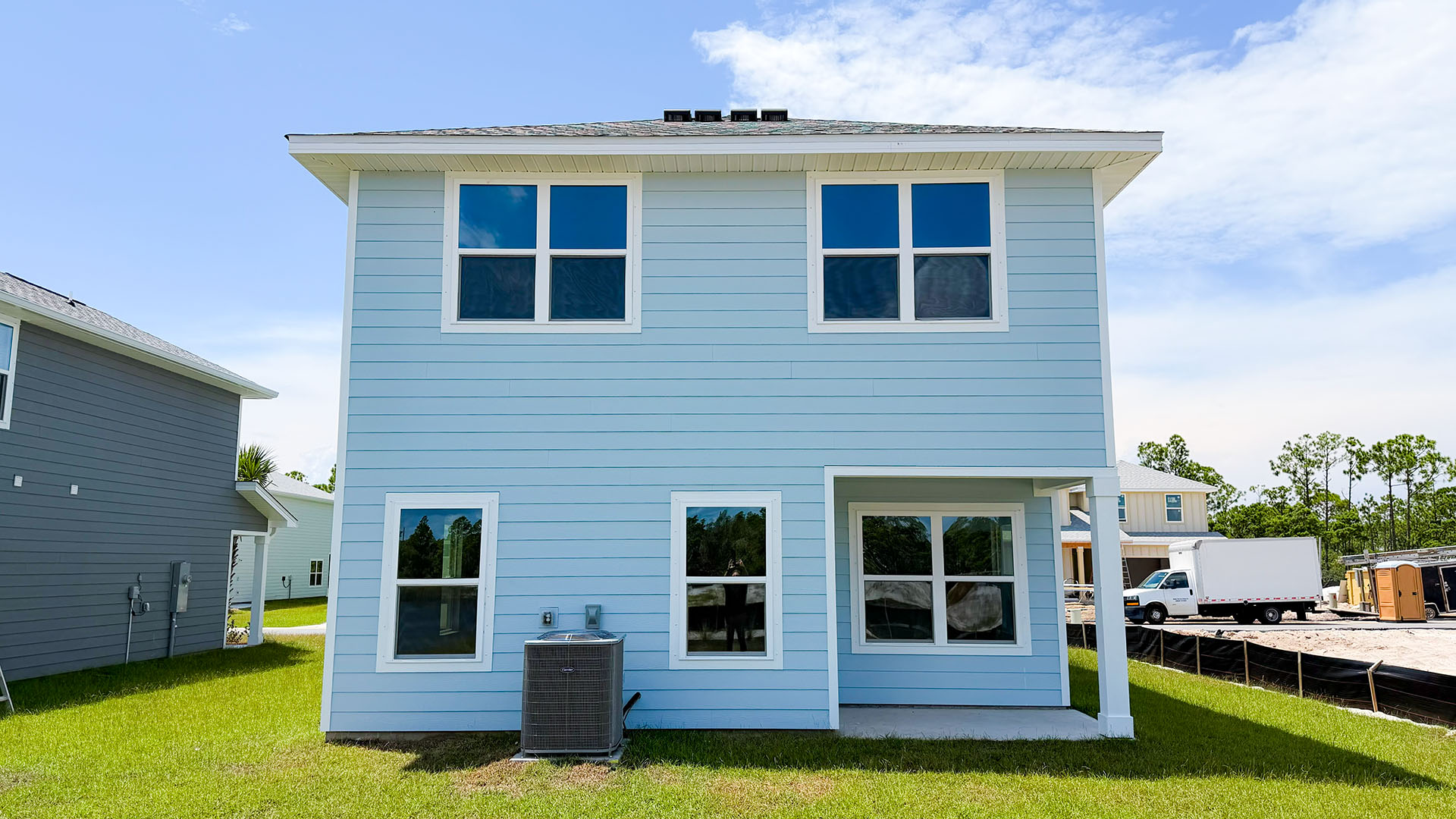 Monroe floor plan at WindMark Beach with Hardie siding and covered front porch and balcony and 1 car garage.