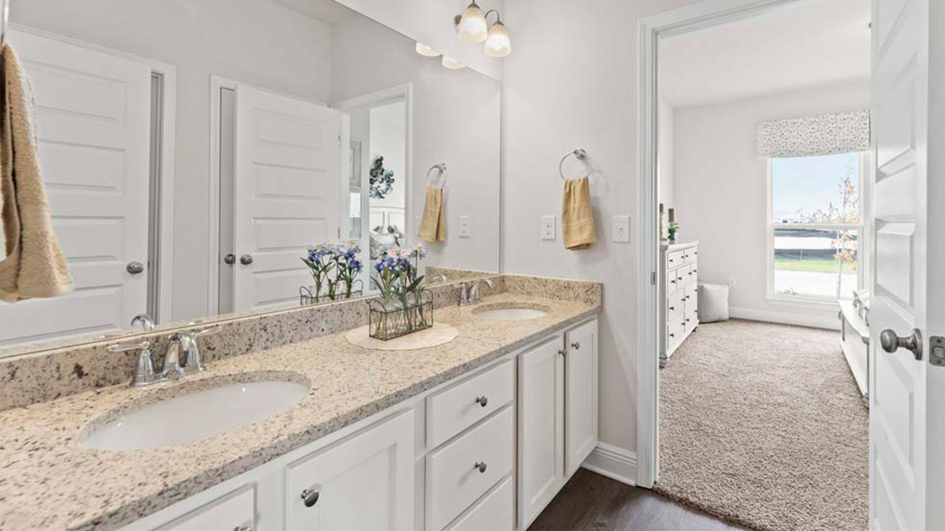 Joint bathroom with double vanity granite countertops and white cabinets with EVP flooring.