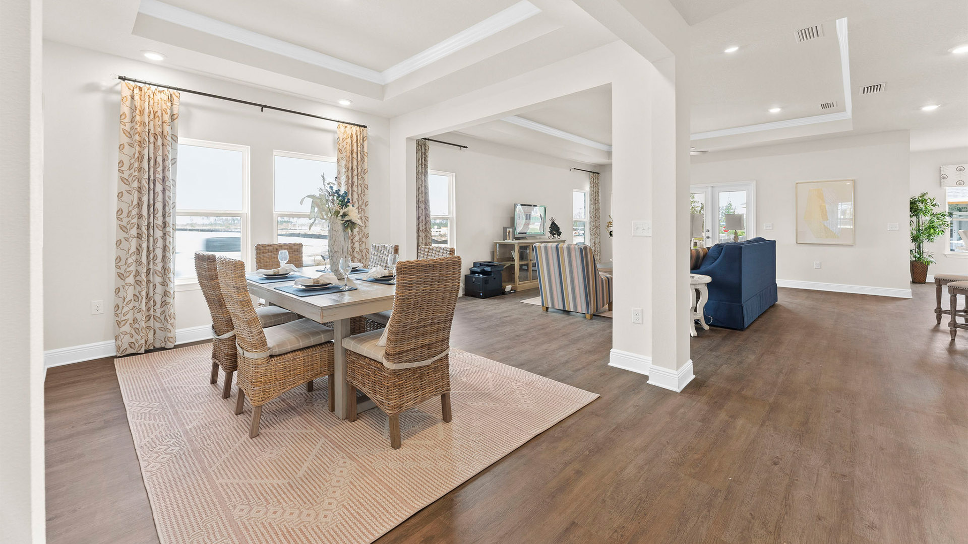 Open dining room and living room with tray ceilings and EVP flooring.