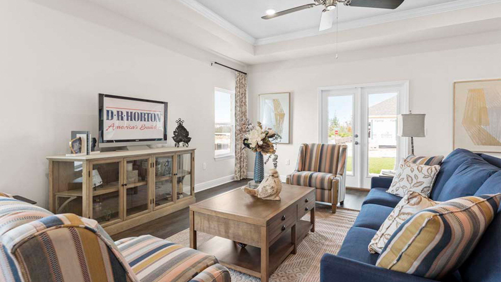 Open living room with EVP flooring and tray ceilings and ceiling fan and back door.