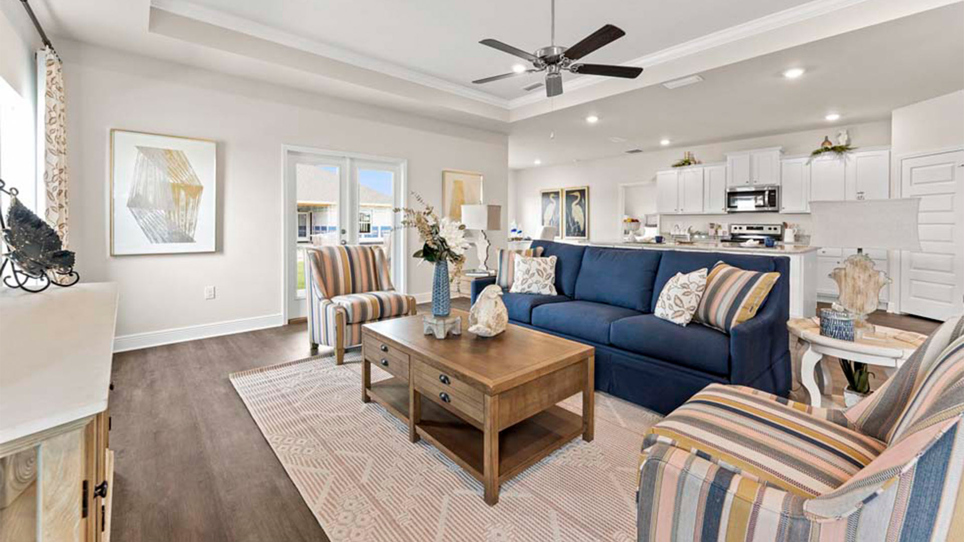 Open living room with EVP flooring and tray ceilings and ceiling fan and back door.