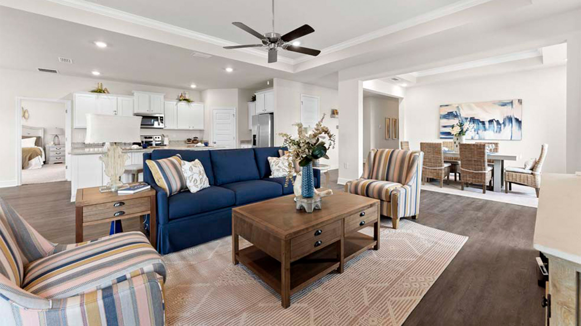 Open living room with EVP flooring and tray ceilings and ceiling fan and back door.