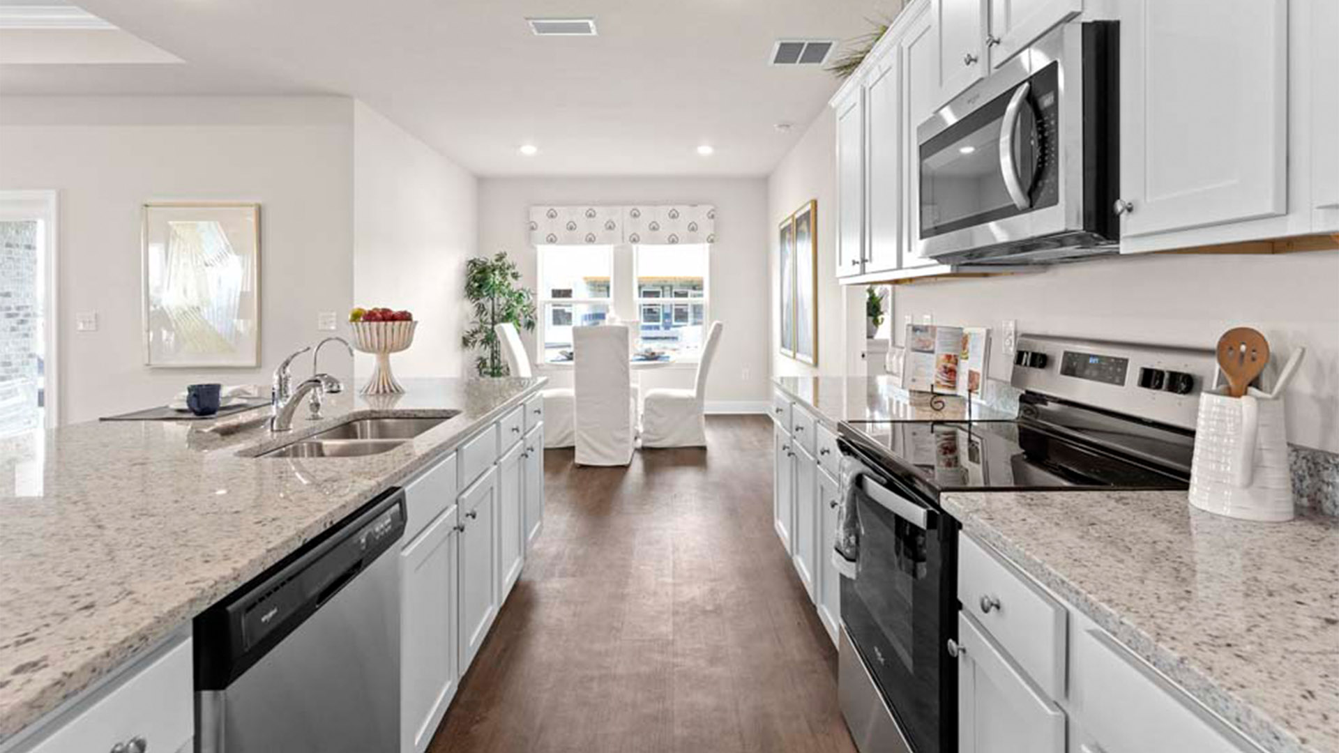Open kitchen with island with granite countertops and stainless-steel appliances and white cabinets and dining area.