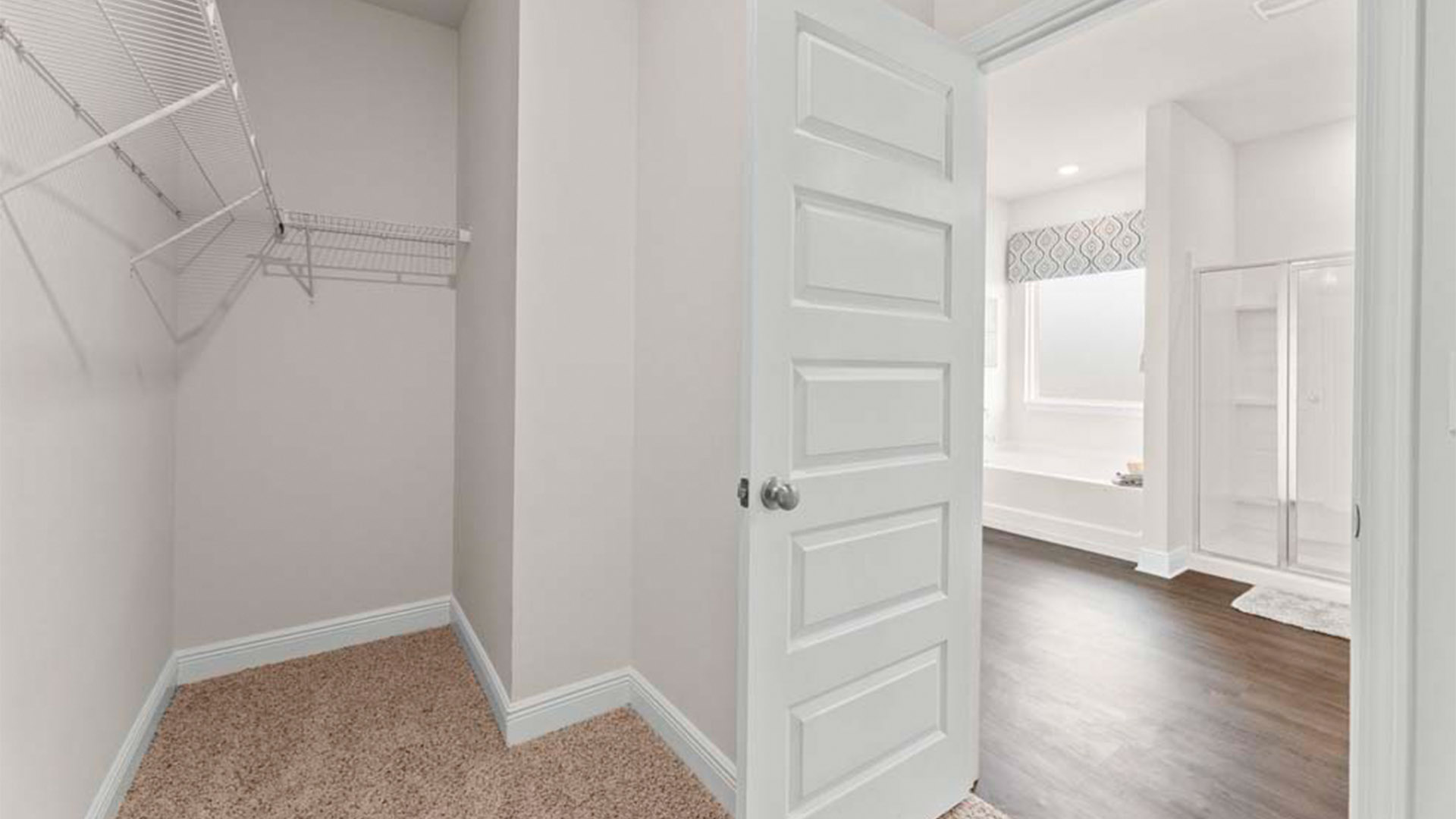 Walk in closet with carpet floors and ventilated shelving.