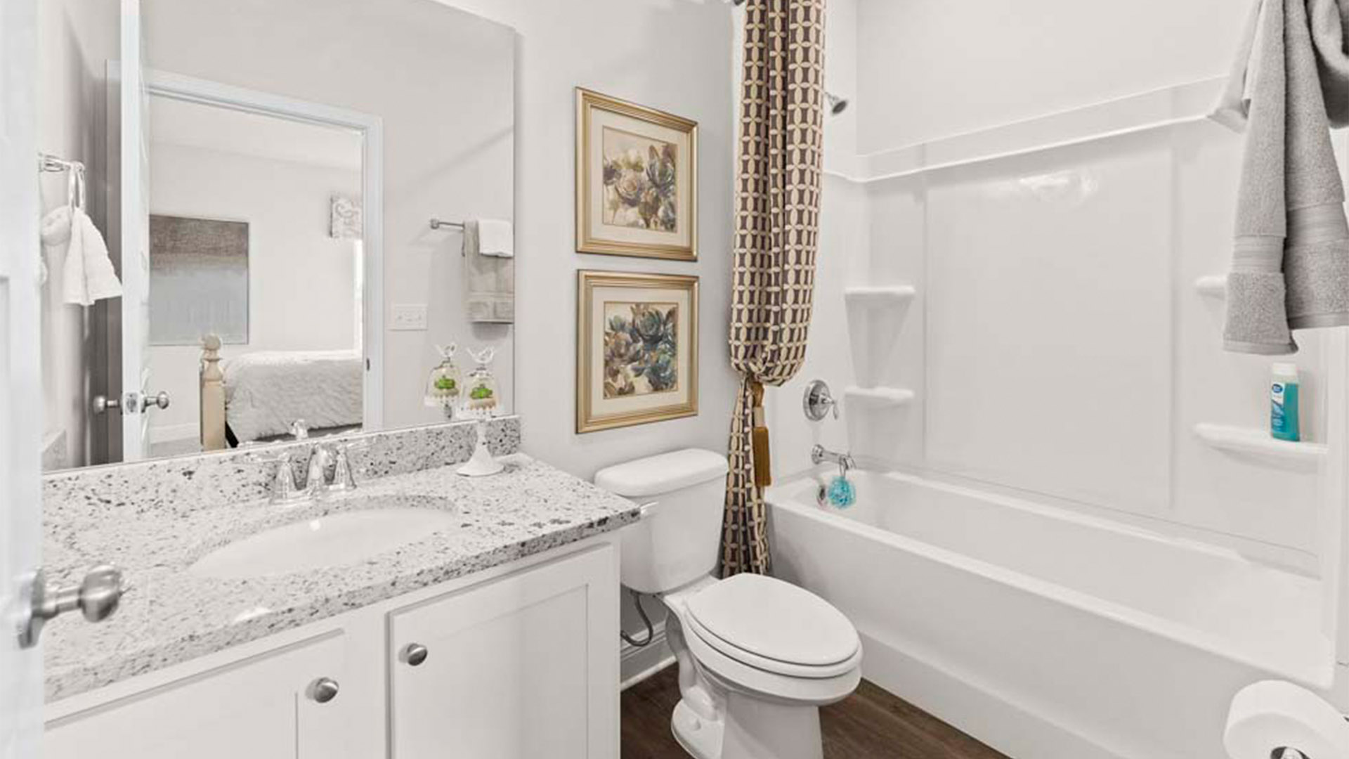 Bathroom with granite countertops and single vanity and white cabinets and EVP flooring and toilet and shower.