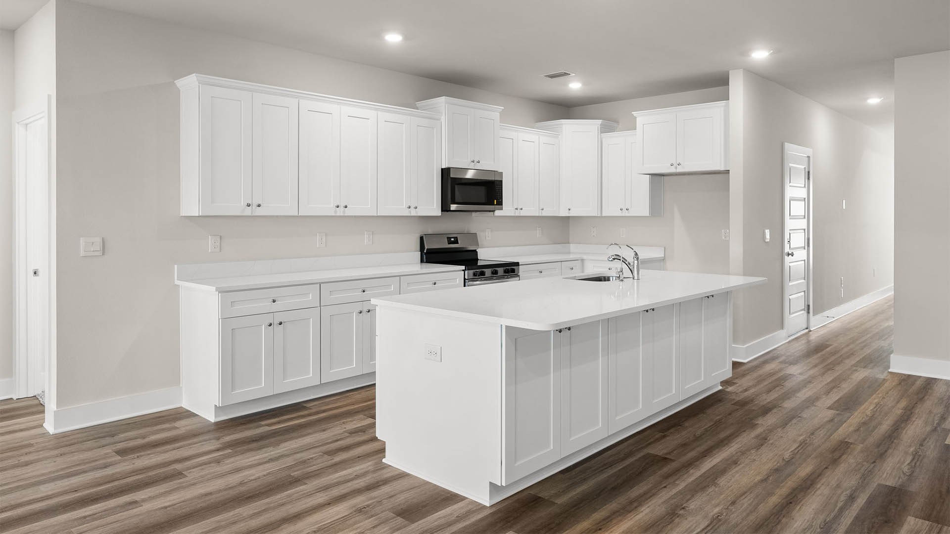 Open kitchen with island with quartz countertops and stainless-steel appliances and white cabinets.