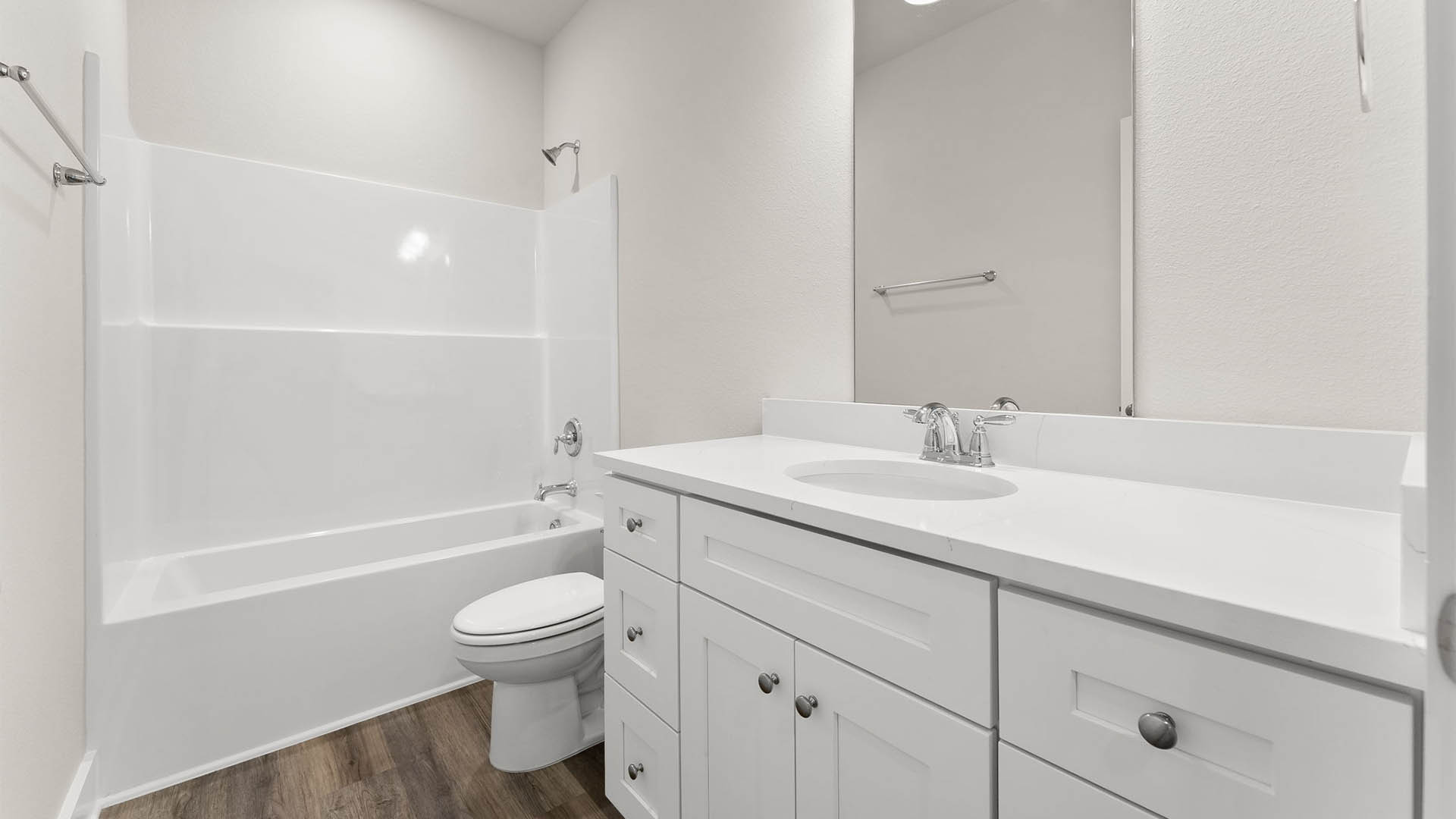 Bathroom with quartz countertops and single vanity and white cabinets and EVP flooring and toilet and shower.